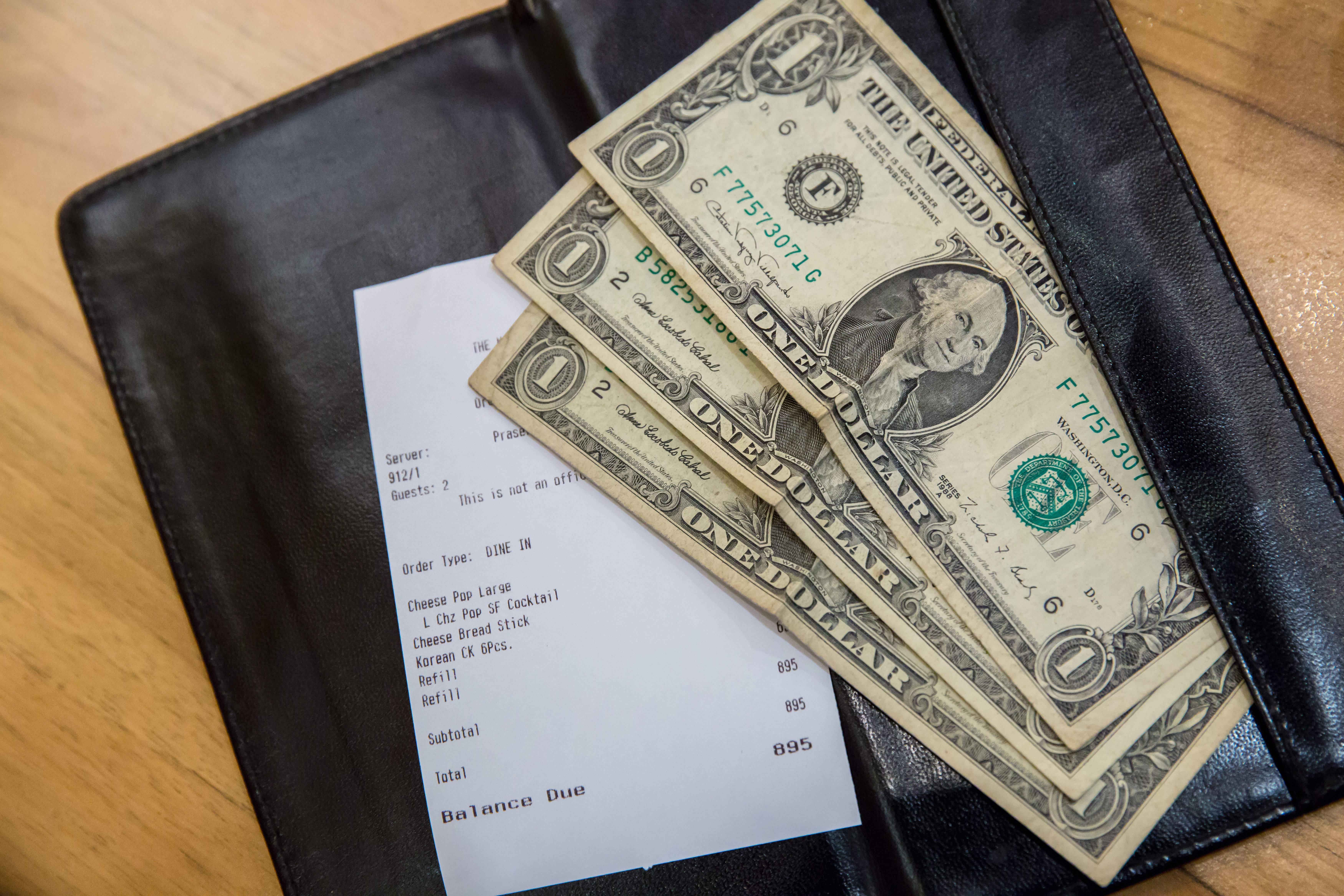 Eine Restaurantrechnung und ein paar Dollar. | Quelle: Shutterstock