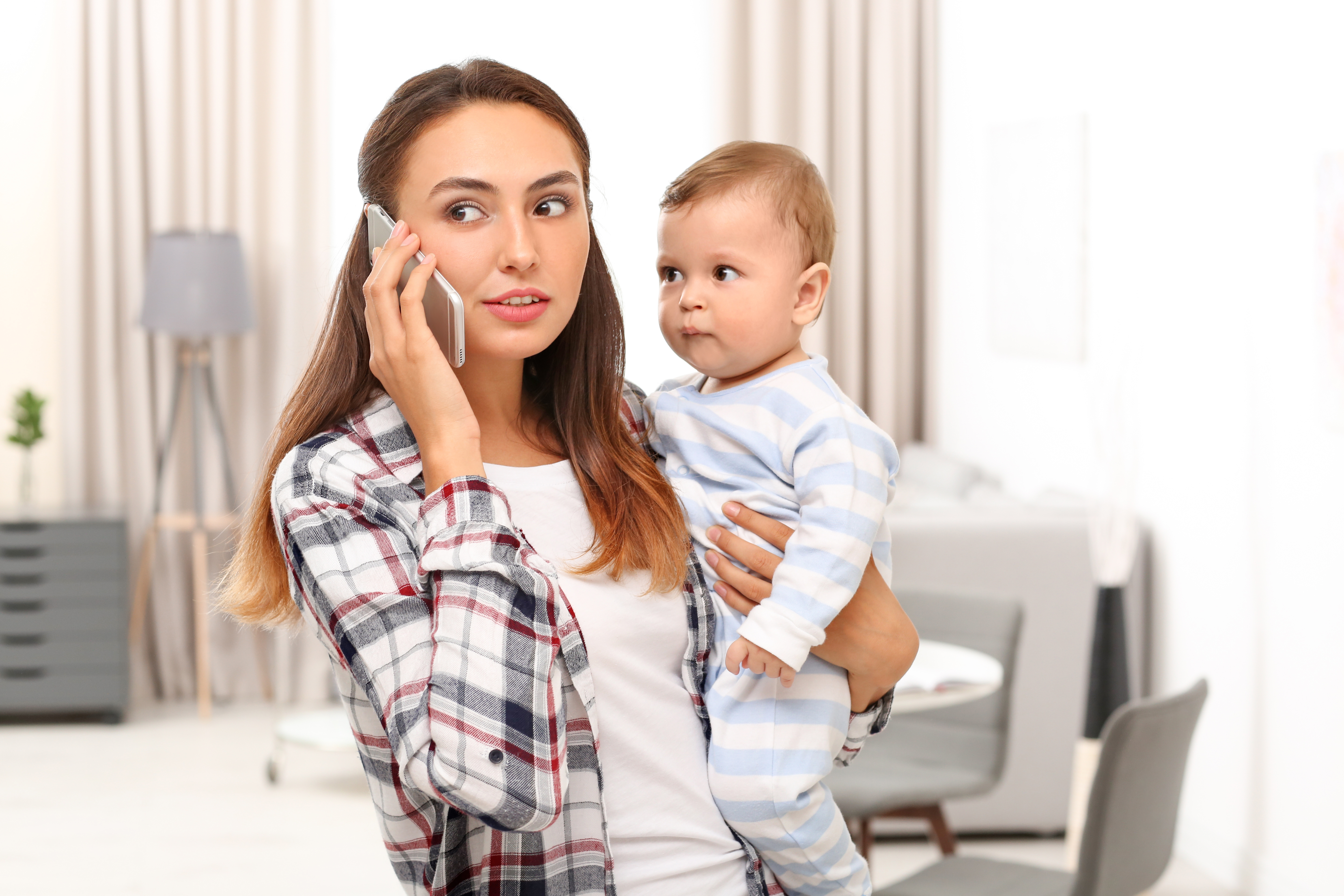 Eine junge Mutter hält ihr Baby im Arm, während sie telefoniert | Quelle: Shutterstock