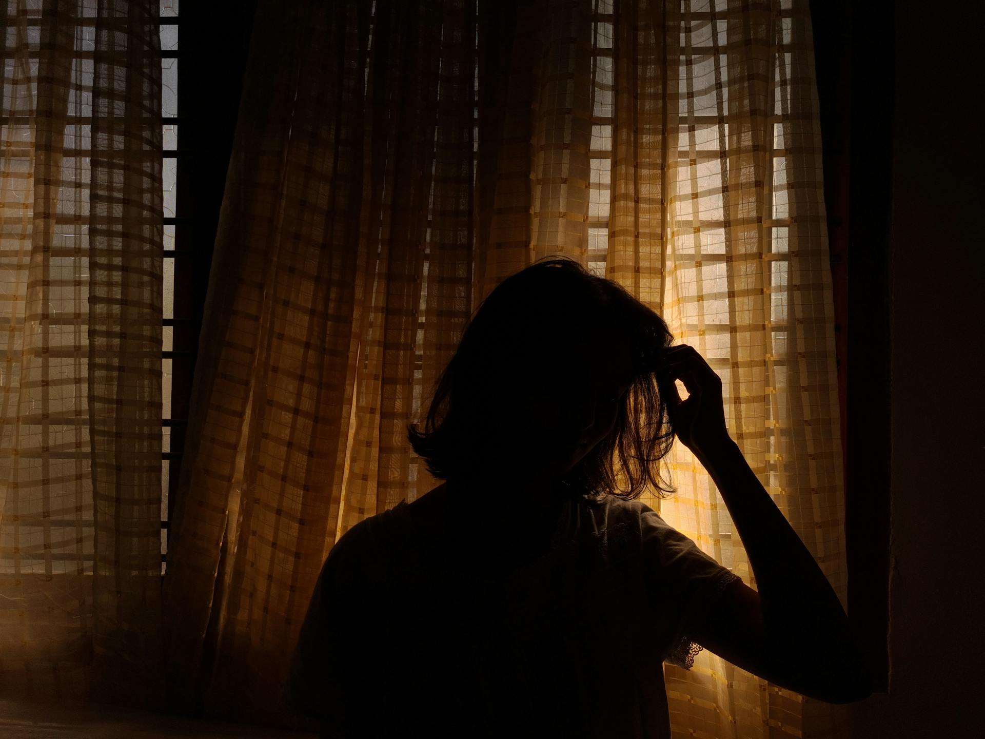 Silhouette einer Frau, die an einem Fenster steht | Quelle: Pexels