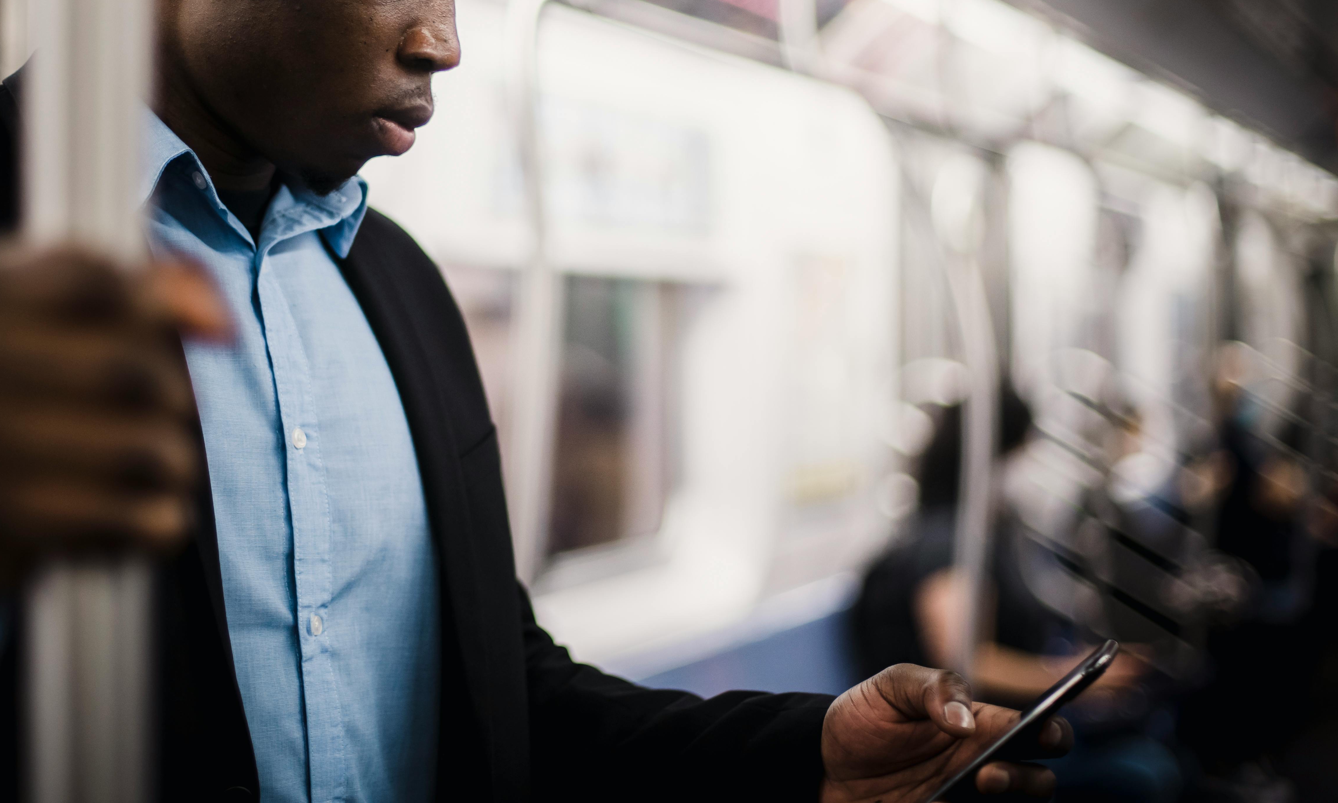 Ein Mann arbeitet mit seinem Handy in einem U-Bahn-Wagen | Quelle: Pexels