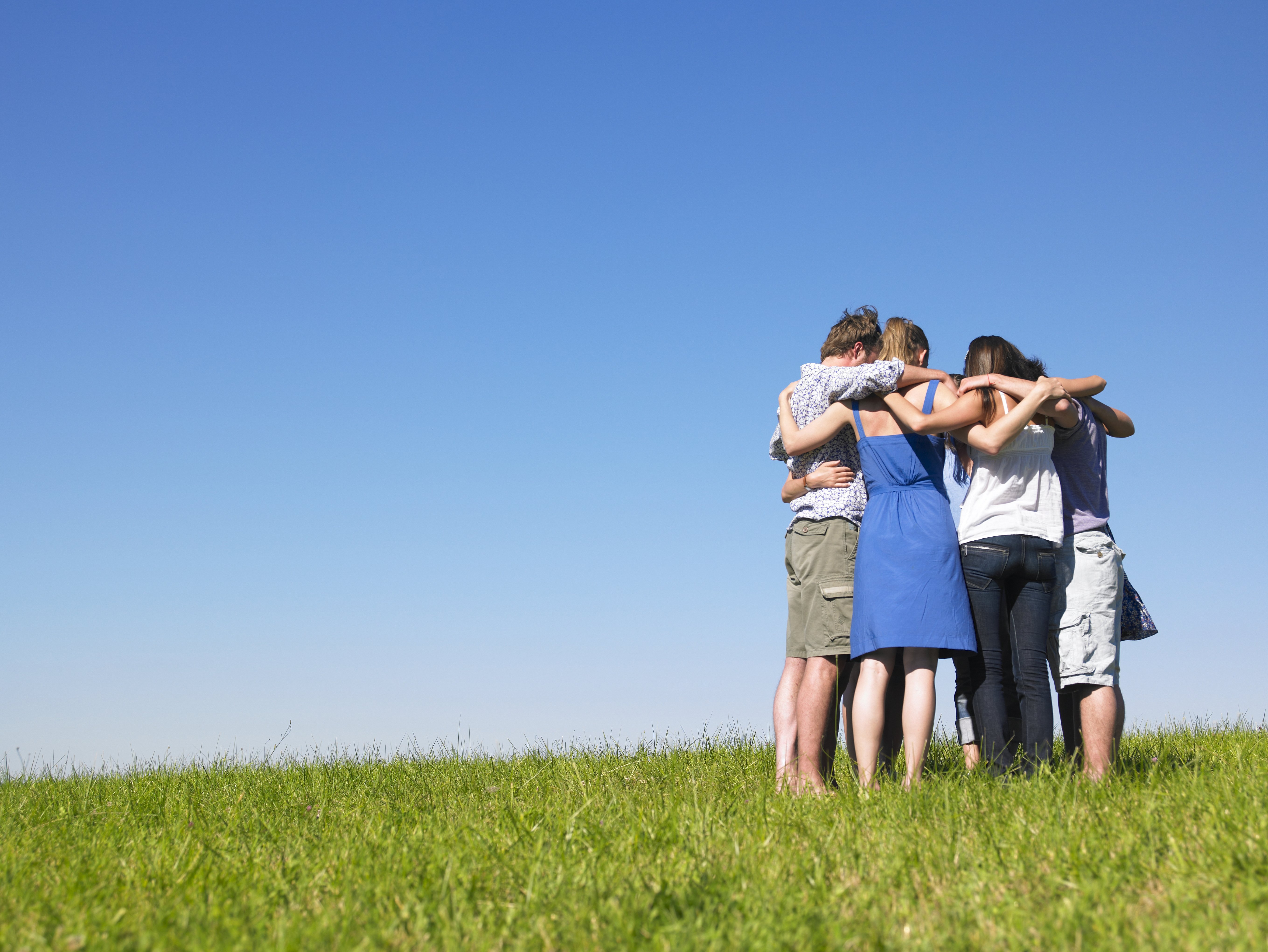 Eine Gruppe von Menschen, die sich auf einem Feld umarmen. | Quelle: Shutterstock