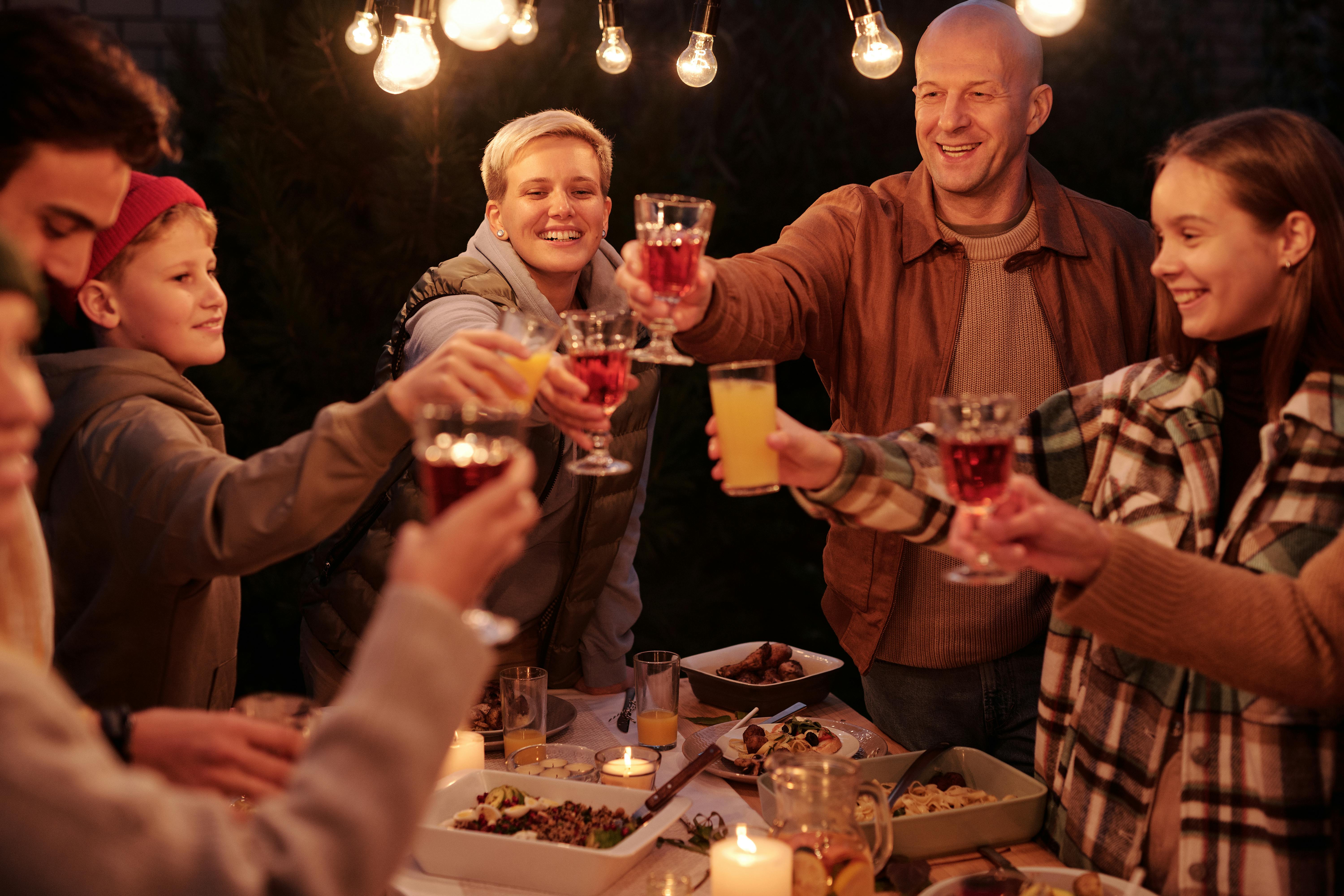 Eine Familie stößt unter Lichtern an | Quelle: Pexels