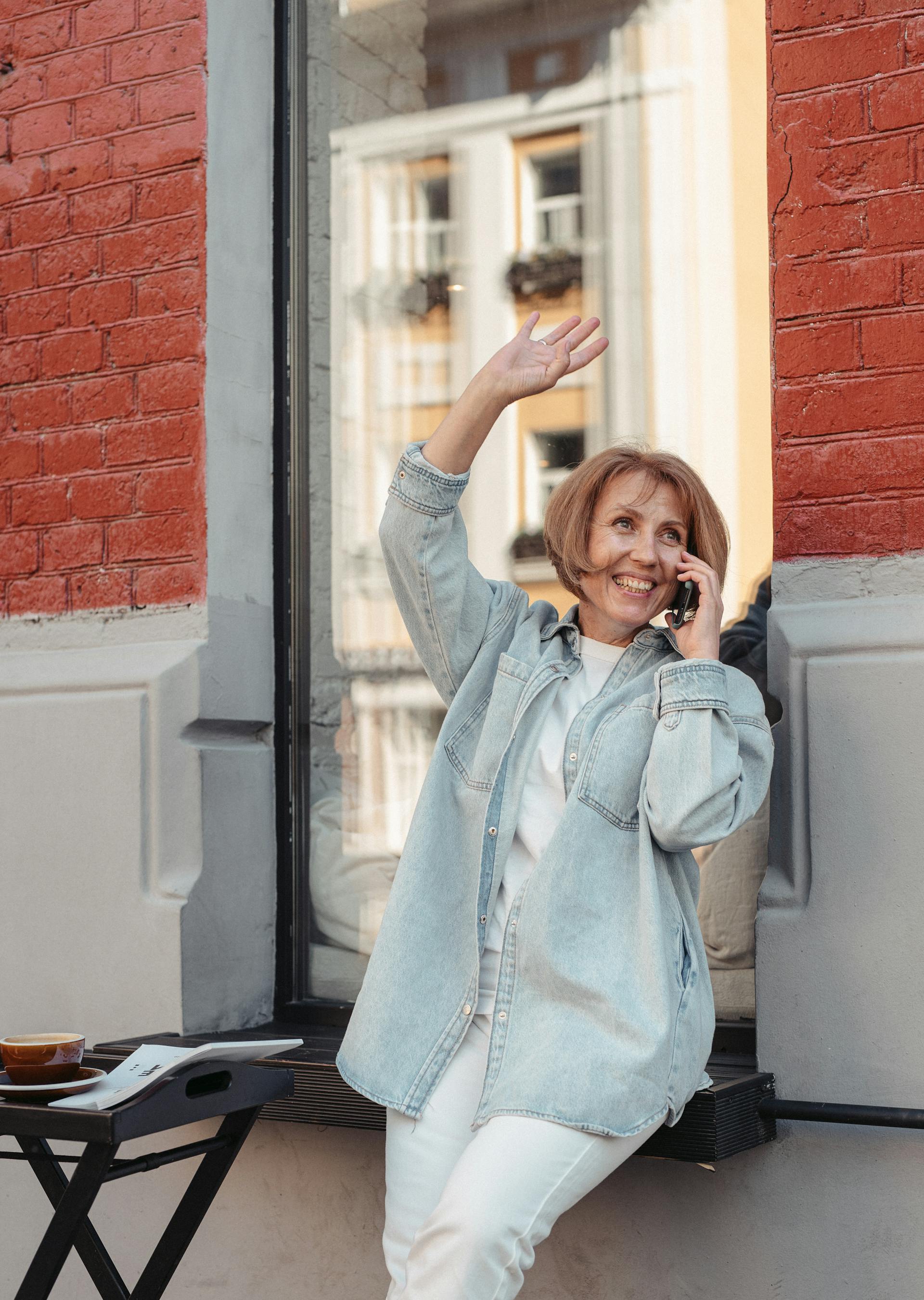 Eine Frau, die lächelt und winkt, während sie ein Gespräch führt | Quelle: Pexels