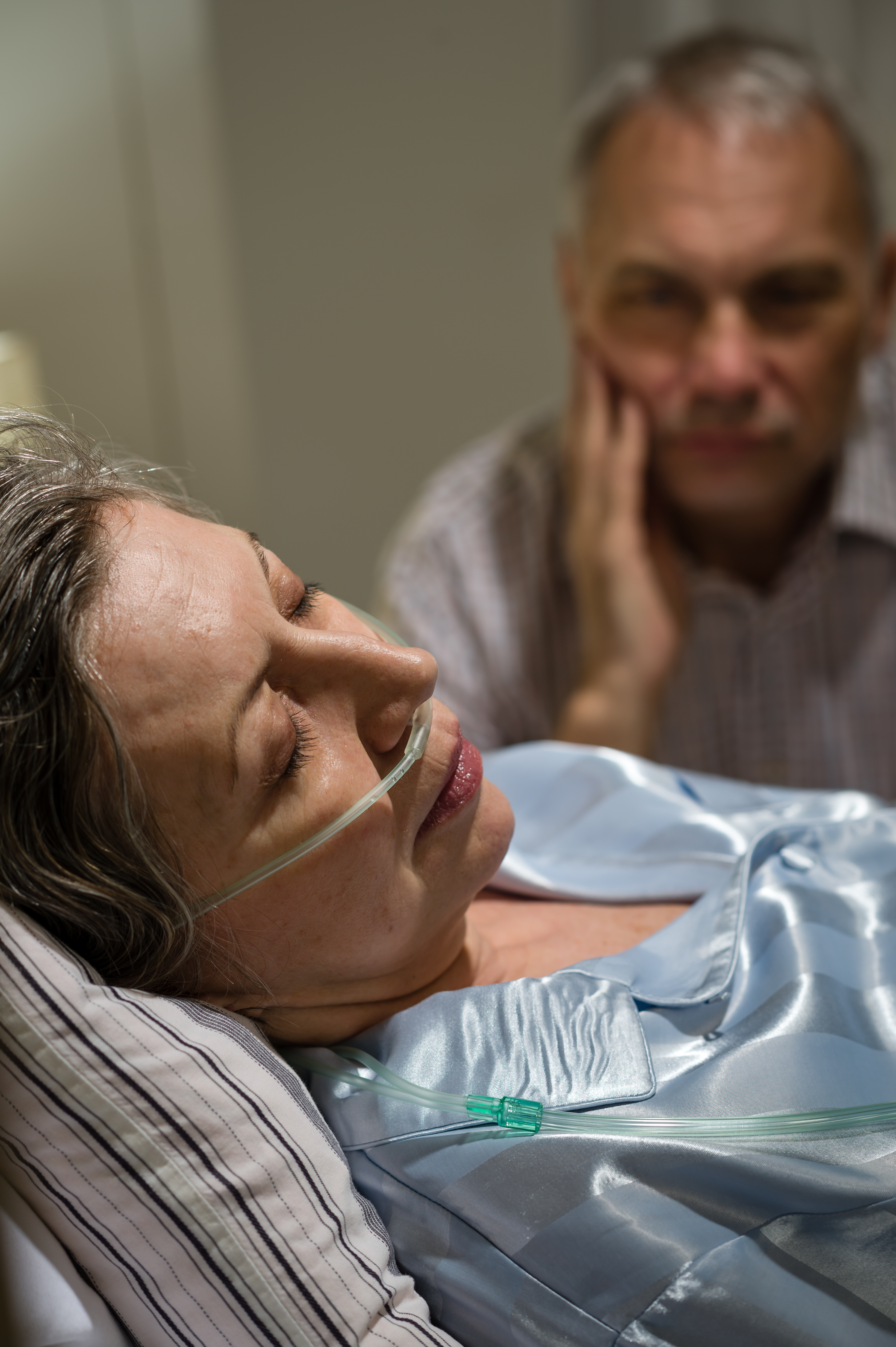 Eine kranke Frau im Krankenhaus mit einem Mann an ihrer Seite | Quelle: Shutterstock