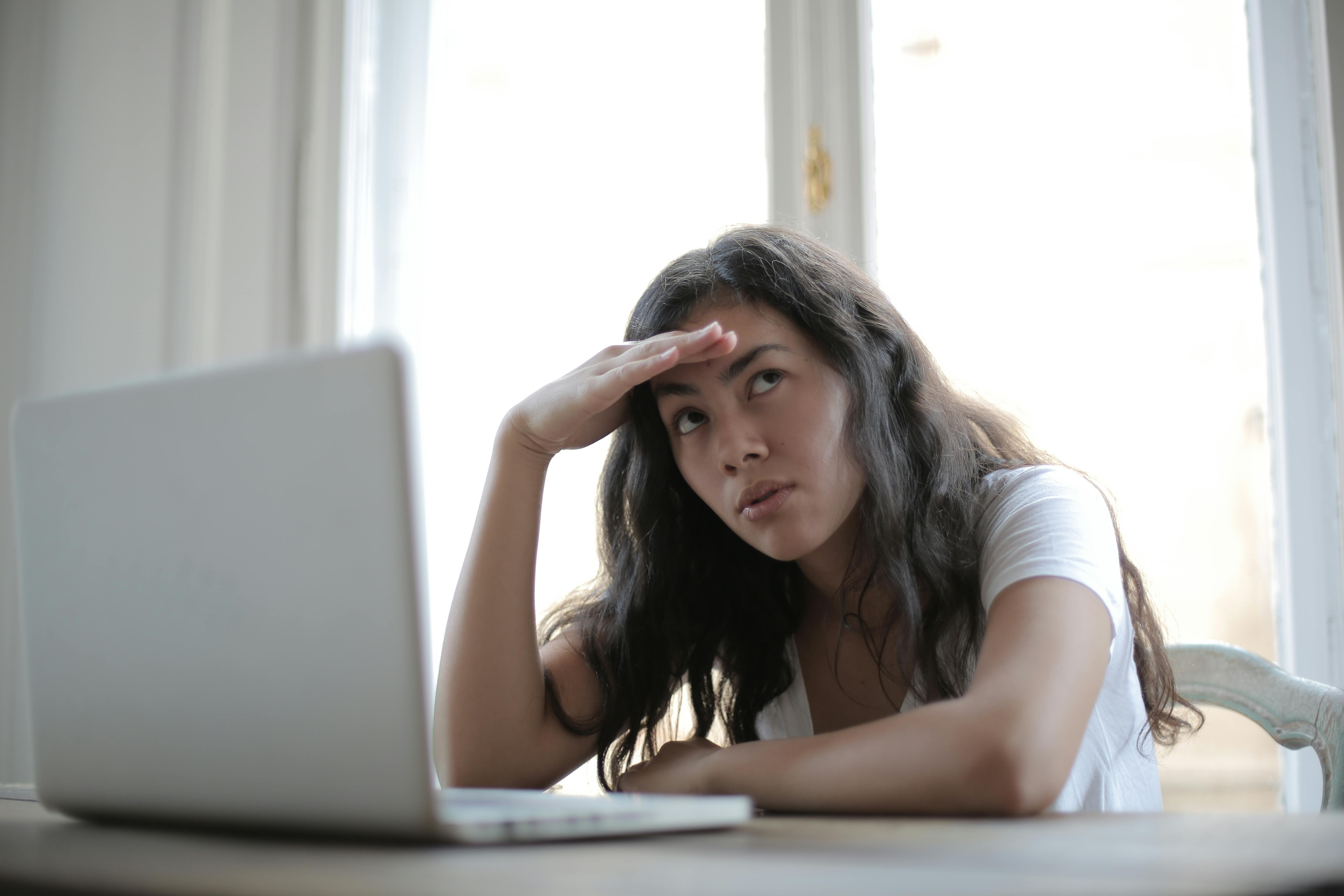 Eine Frau, die vor einem Computer sitzt und über etwas nachdenkt | Quelle: Pexels