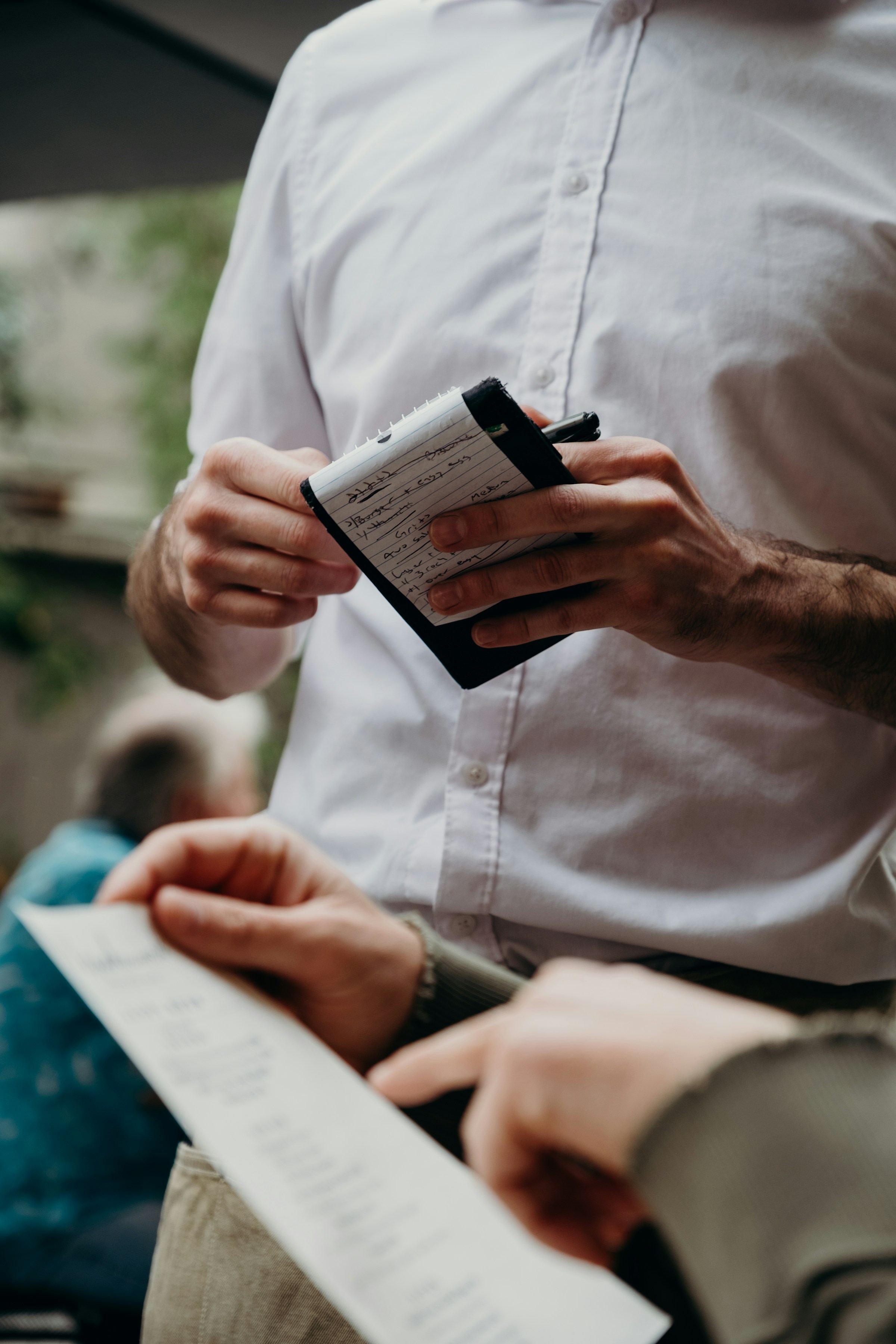 Um garçom em um restaurante fica ao lado de um cliente verificando a conta | Fonte: Unsplash