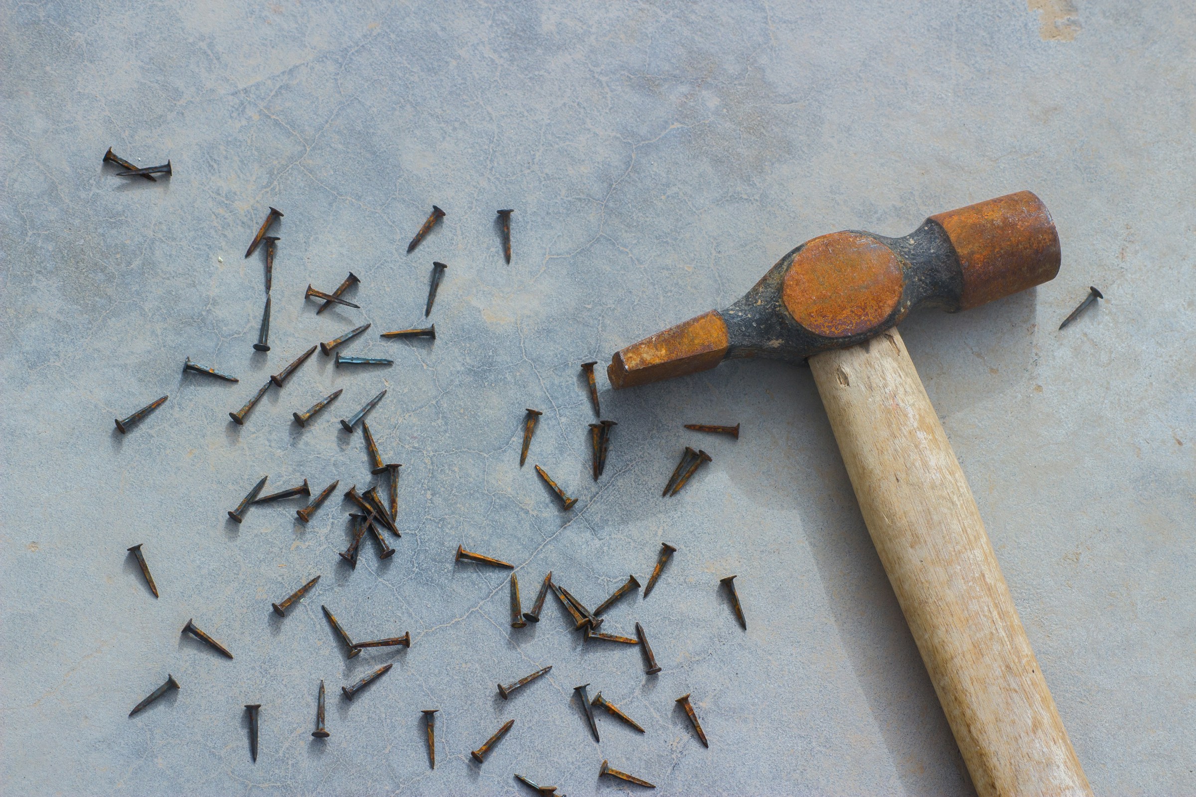 Nägel in der Nähe eines Hammers verstreut | Quelle: Unsplash