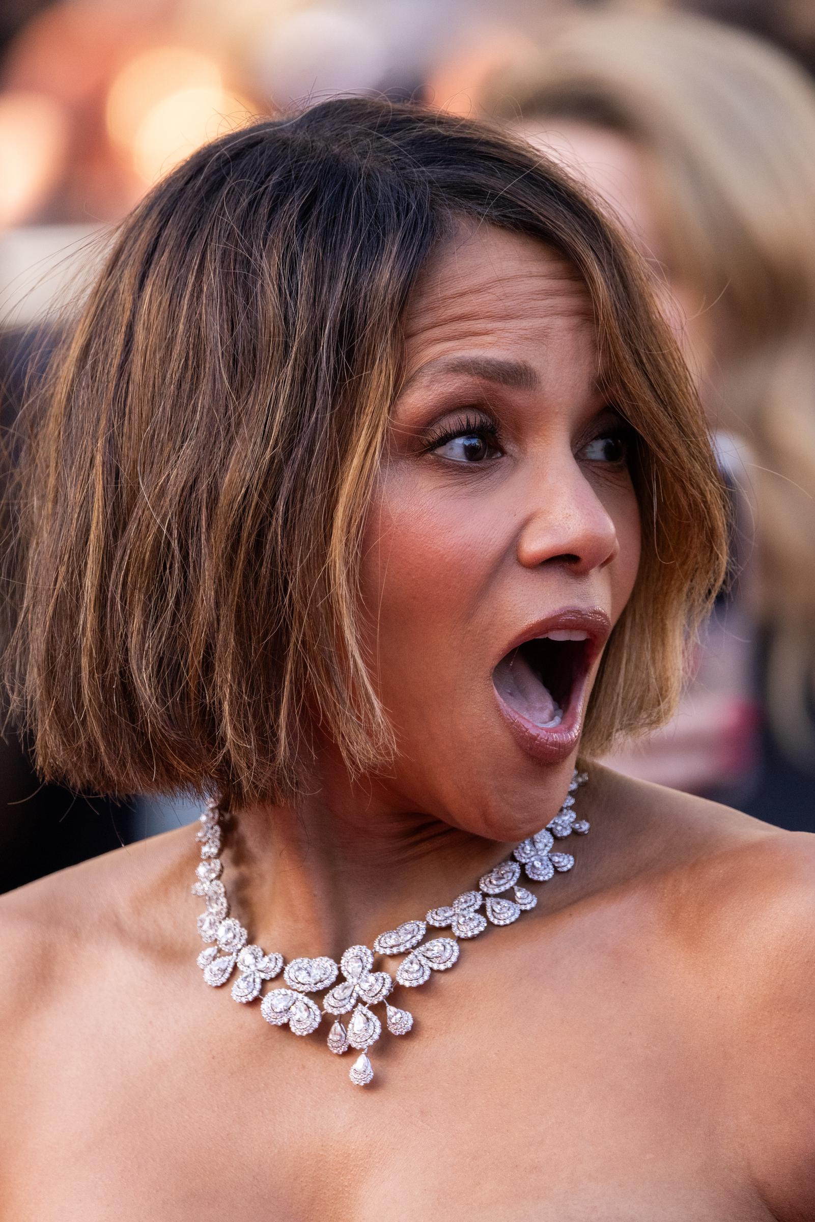 Halle Berry reagiert mit einem überraschten Gesichtsausdruck, während sie auf dem roten Teppich in Cannes steht. Ihr glamouröser Look bestand aus einem sanften, neutralen Make-up, voluminösen Wimpern und einem schlanken, kinnlangen Bob mit dezenten Strähnchen.