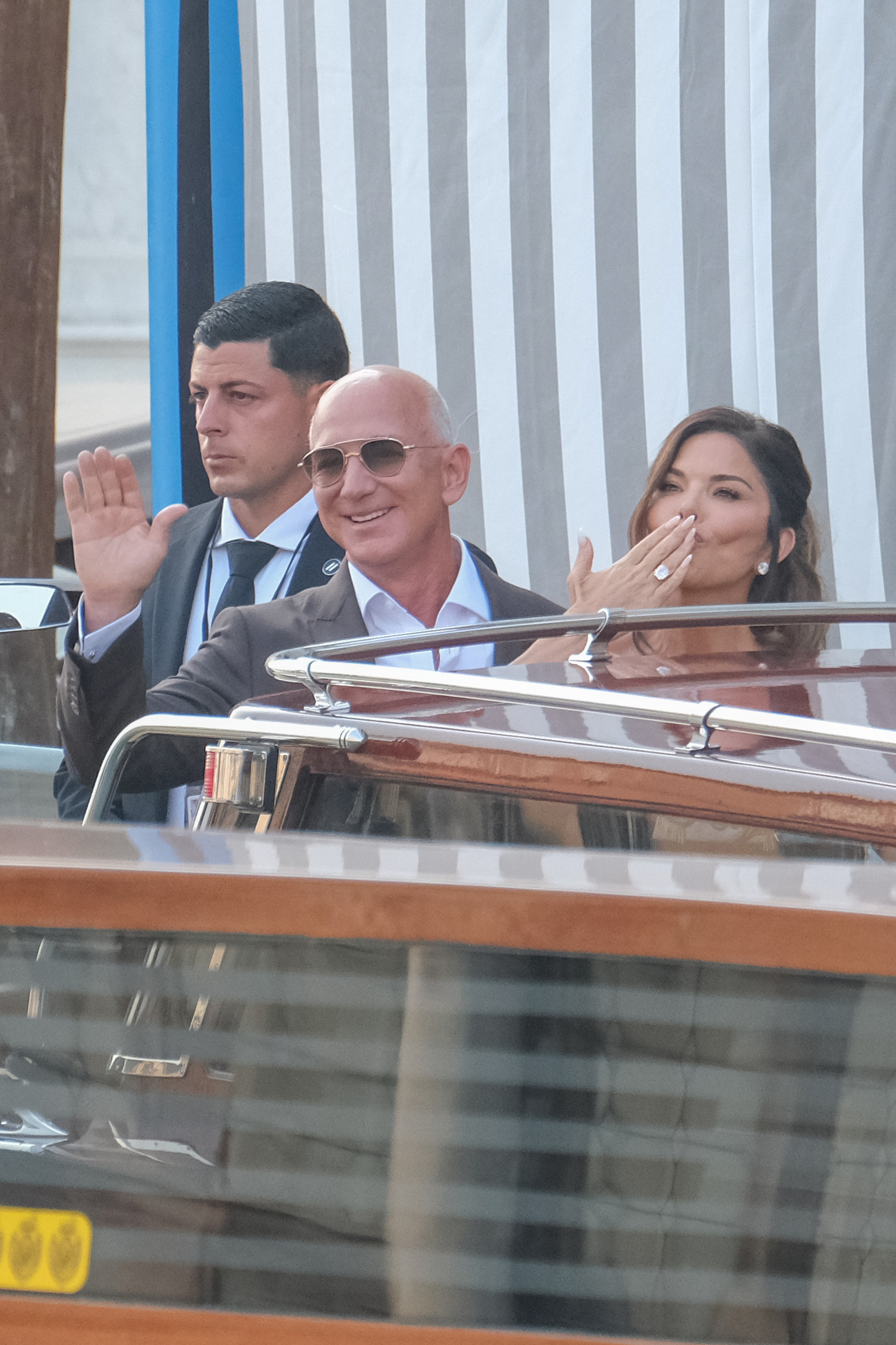 Jeff Bezos und Lauren Sánchez an Bord eines Bootes. Sánchez wirft der Menge einen Kuss zu. | Quelle: Getty Images