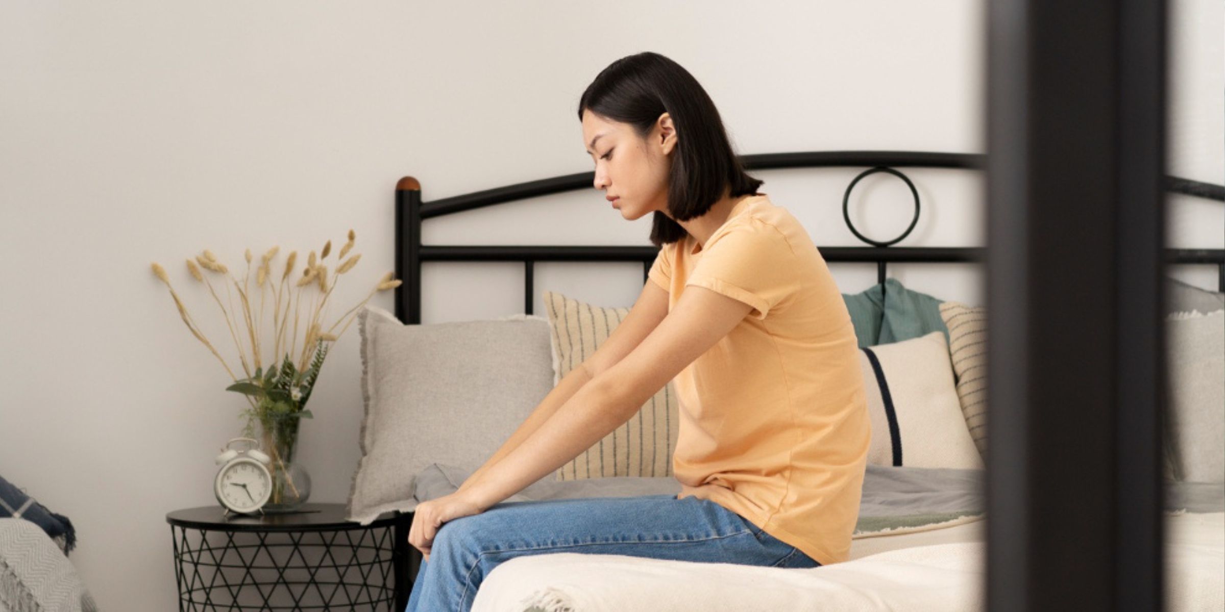 Eine traurige Frau sitzt auf ihrem Bett | Quelle: Freepik