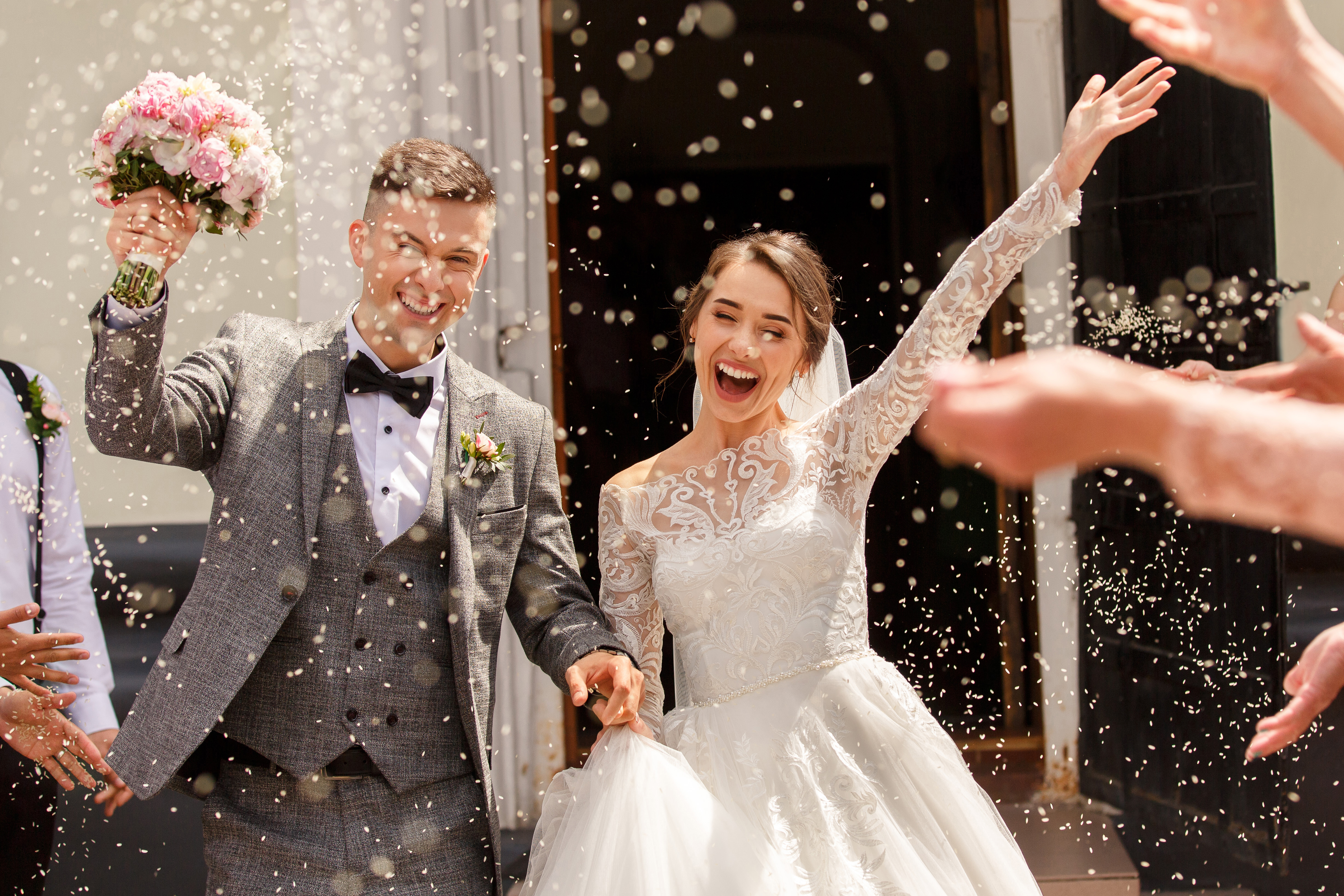 Braut und Bräutigam jubeln bei ihrer Hochzeitsfeier | Quelle: Shutterstock