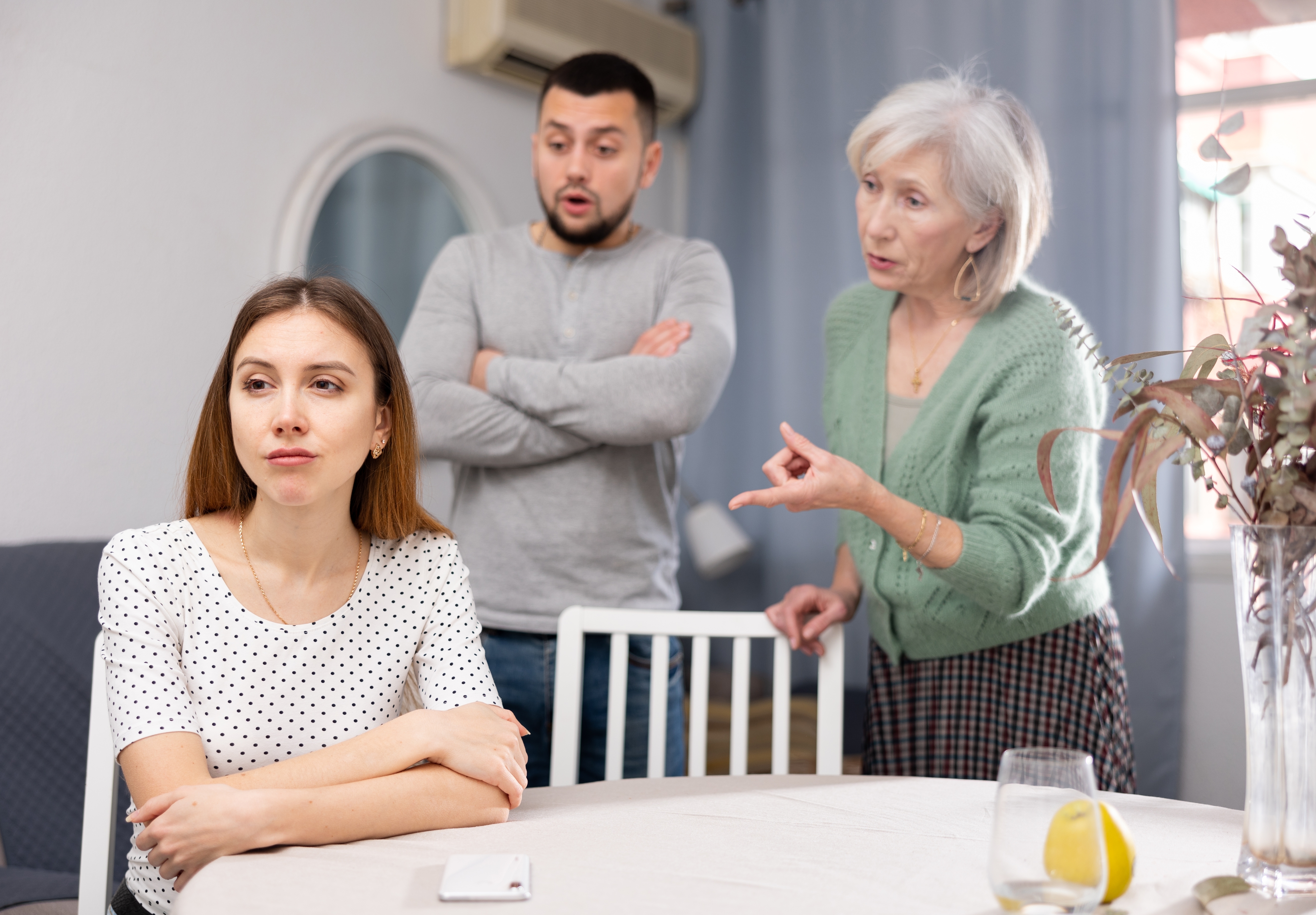 Eine emotionale Frau schimpft mit ihrem Mann und seiner Mutter | Quelle: Shutterstock