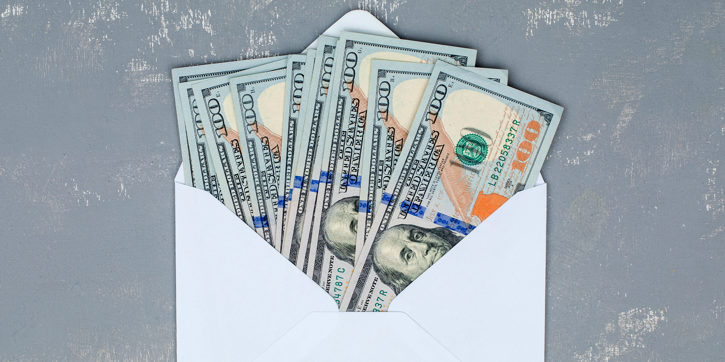Ein offener weißer Umschlag, gefüllt mit 100-Dollar-Scheinen | Quelle: Shutterstock