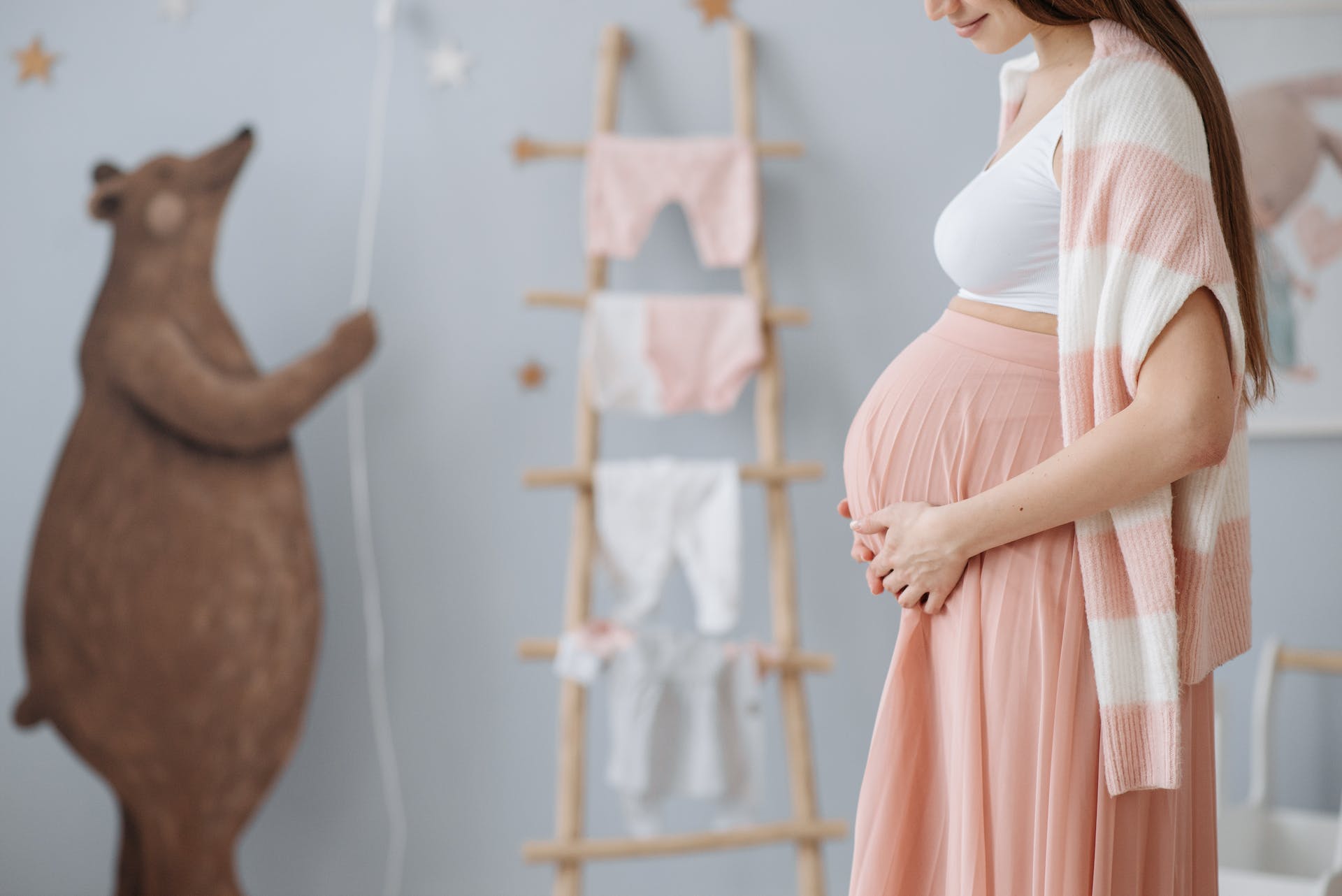 Eine schwangere Frau, die ihren Bauch hält, während sie in einem Kinderzimmer ist | Quelle: Pexels