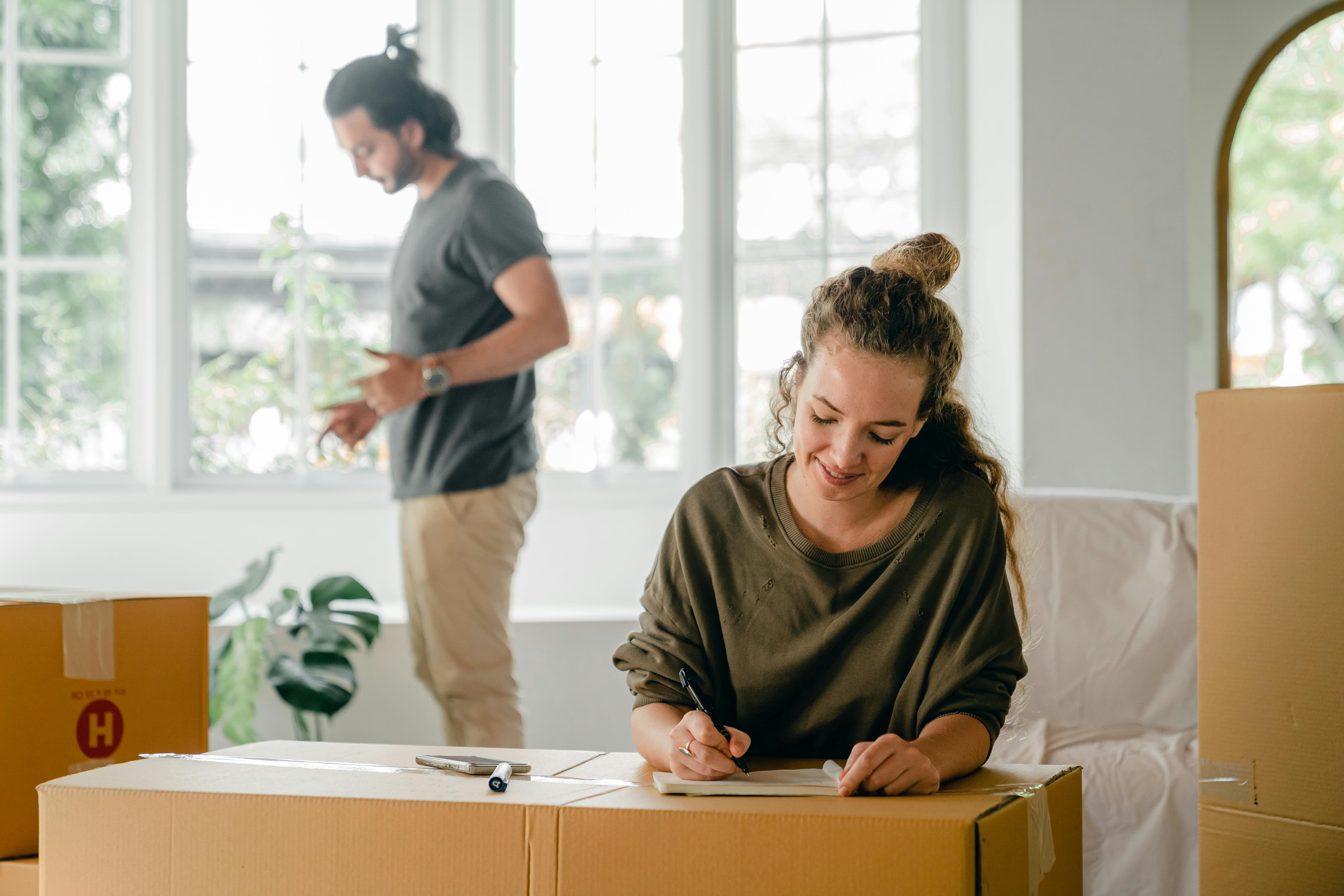 Mann und Frau ziehen in ein neues Haus ein, wobei die Frau einige Papiere unterschreibt | Quelle: Pexels