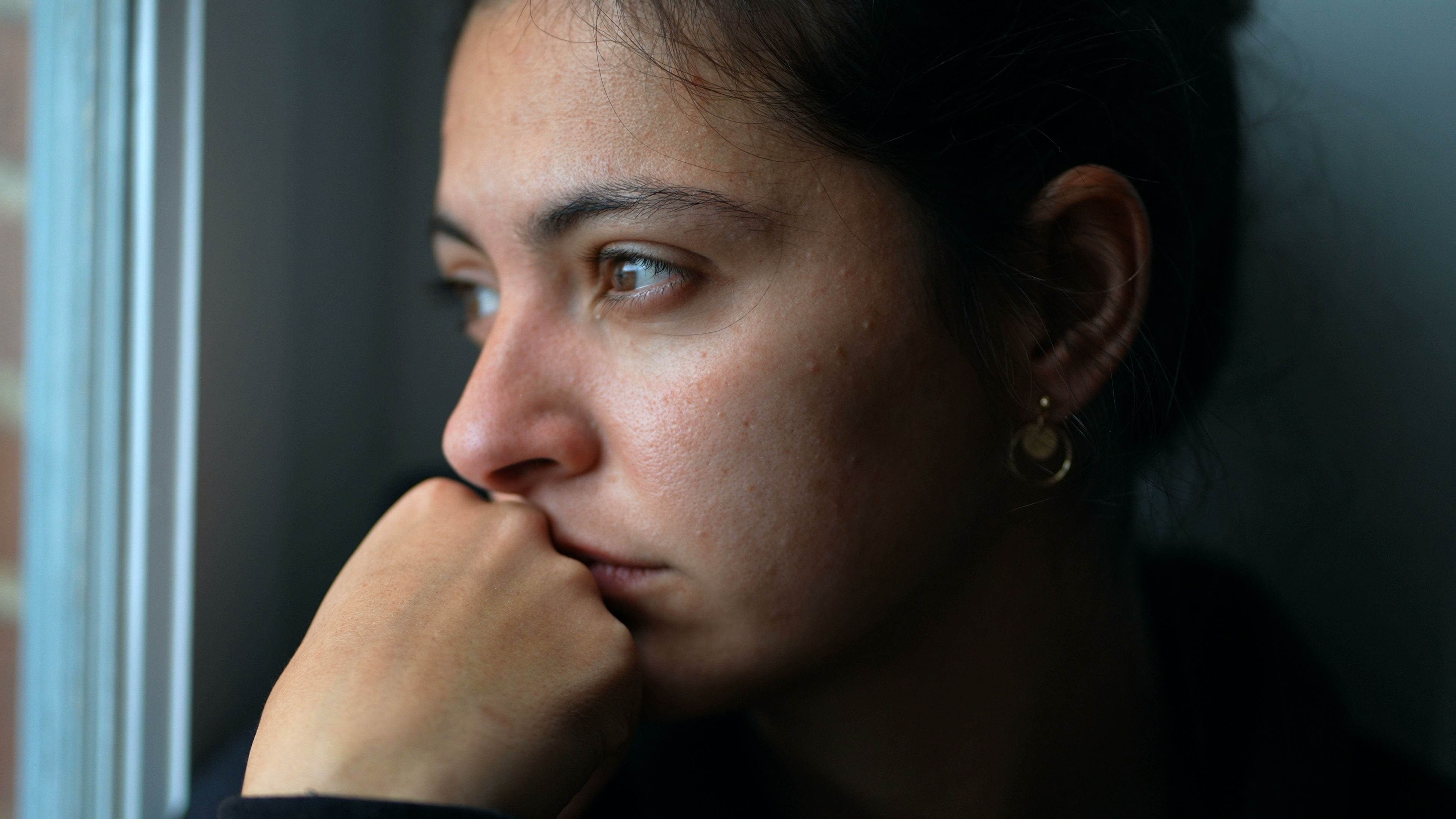Eine junge Frau, die gedankenverloren durch das Fenster schaut | Quelle: Shutterstock