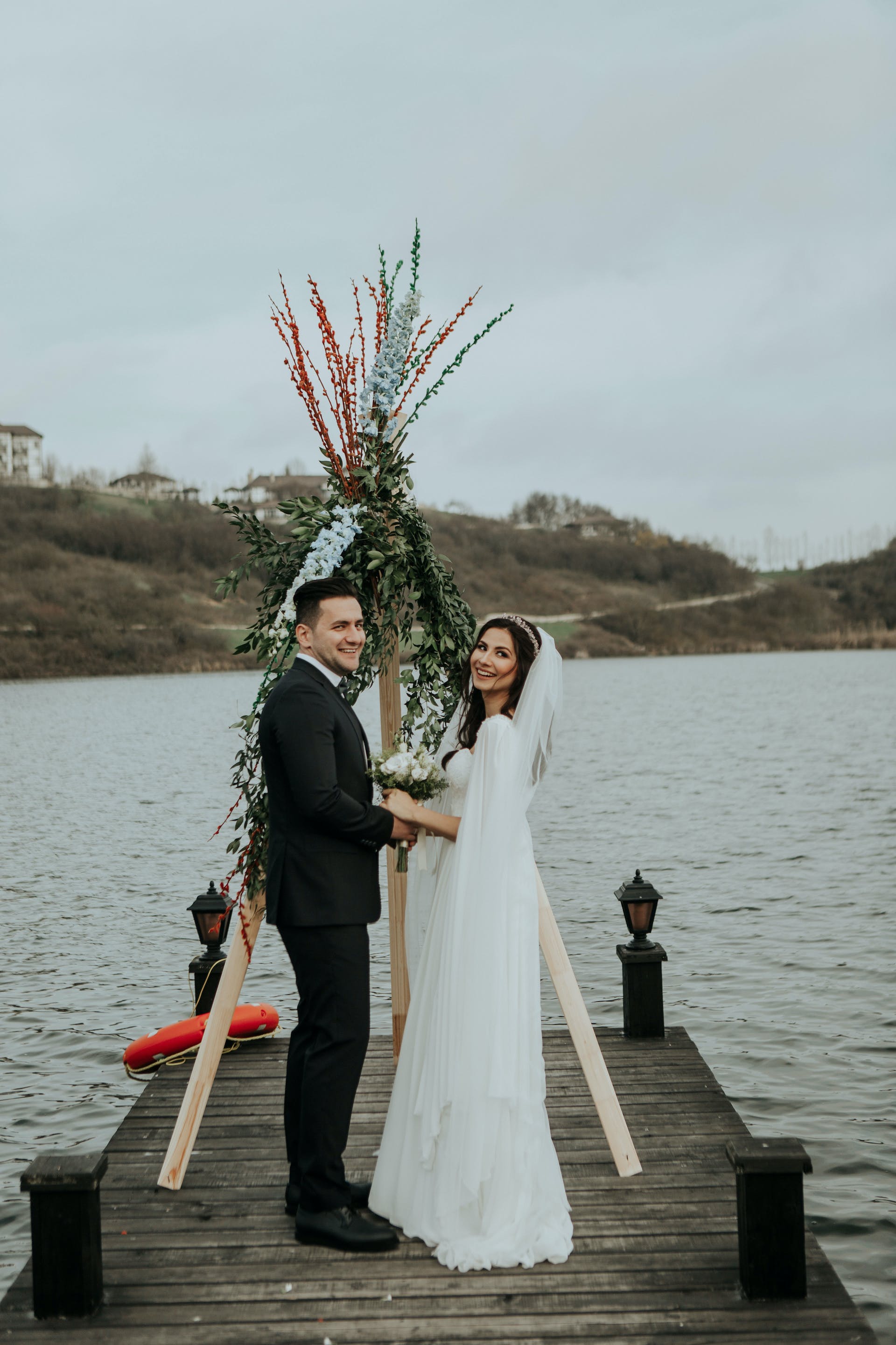 Eine Braut und ein Bräutigam stehen auf einem Pier | Quelle: Pexels