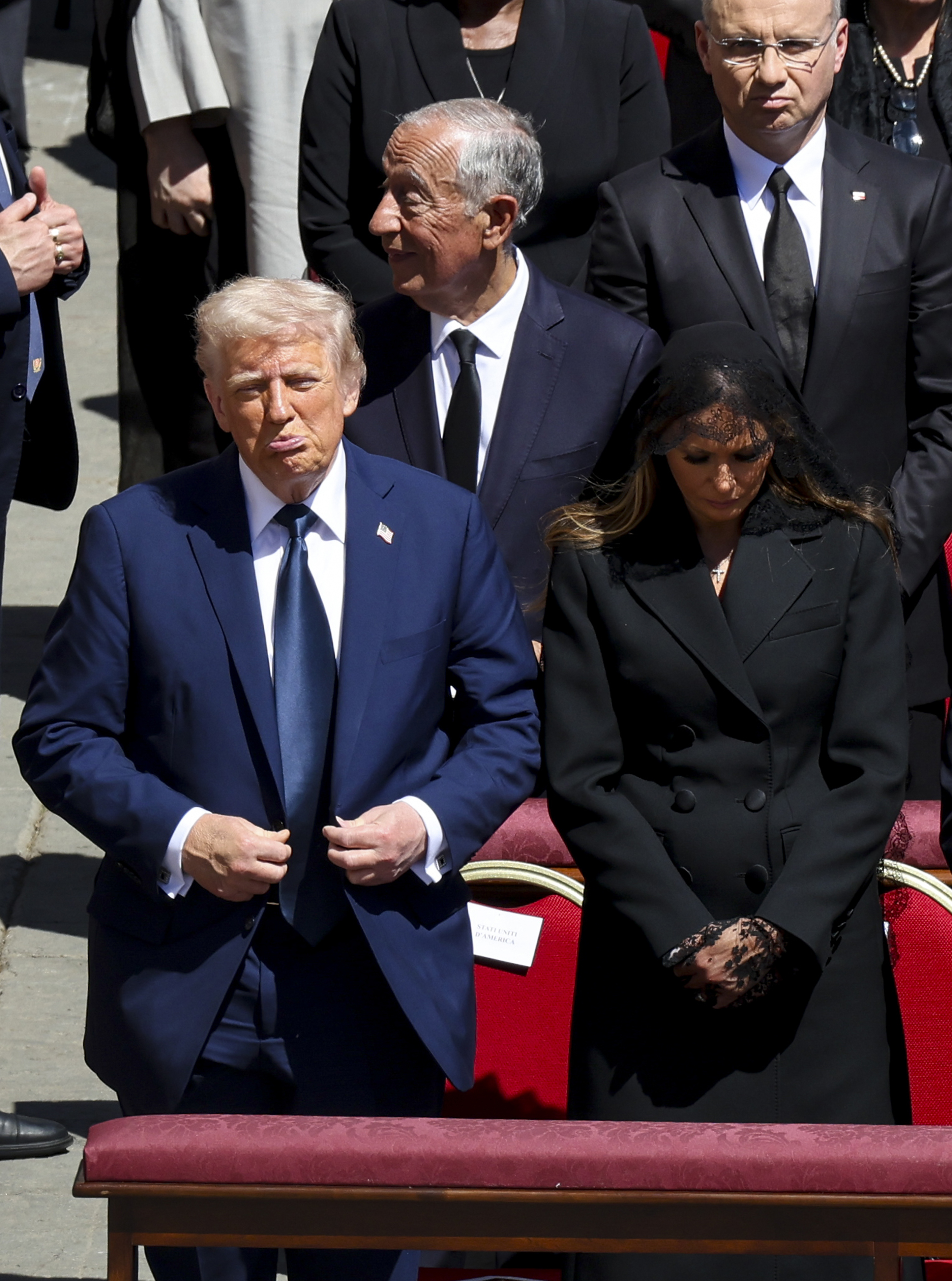 Donald Trump schmollt, während Melania Trump ihren Kopf verneigt. | Quelle: Getty Images
