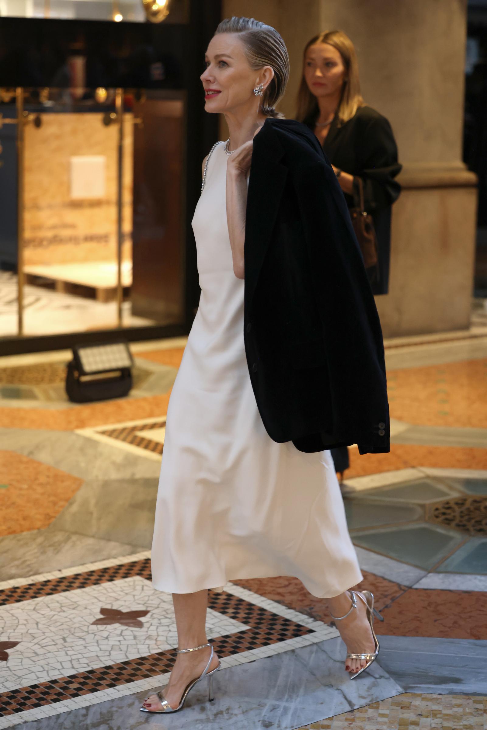 Watts schlendert in einem weißen Midikleid und silbernen Pumps durch den Saal, eine schwarze Jacke über die Schultern geworfen. | Quelle: Getty Images
