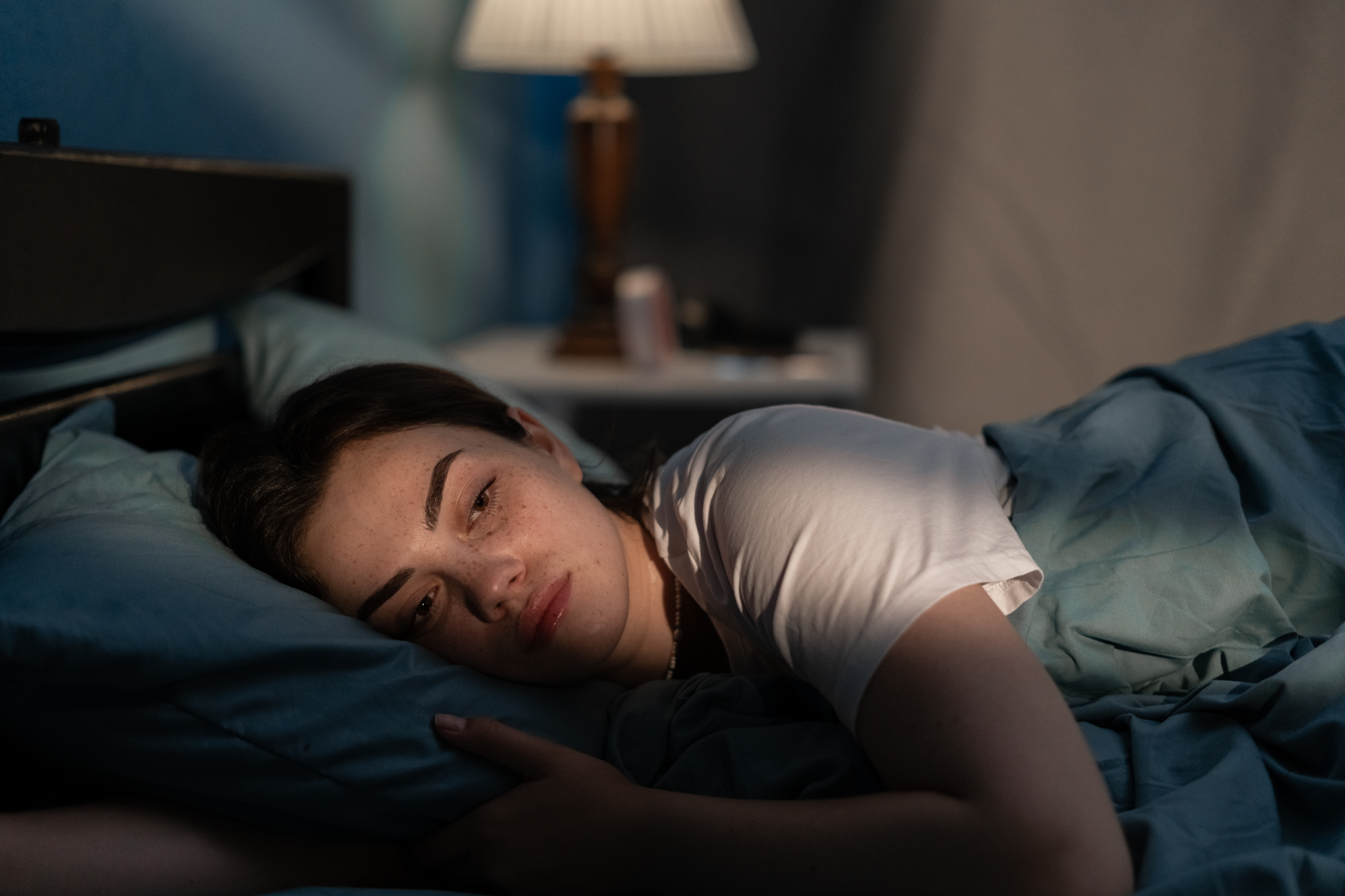 Junge traurige Frau, die spät in der Nacht im Bett liegt | Quelle: Getty Images