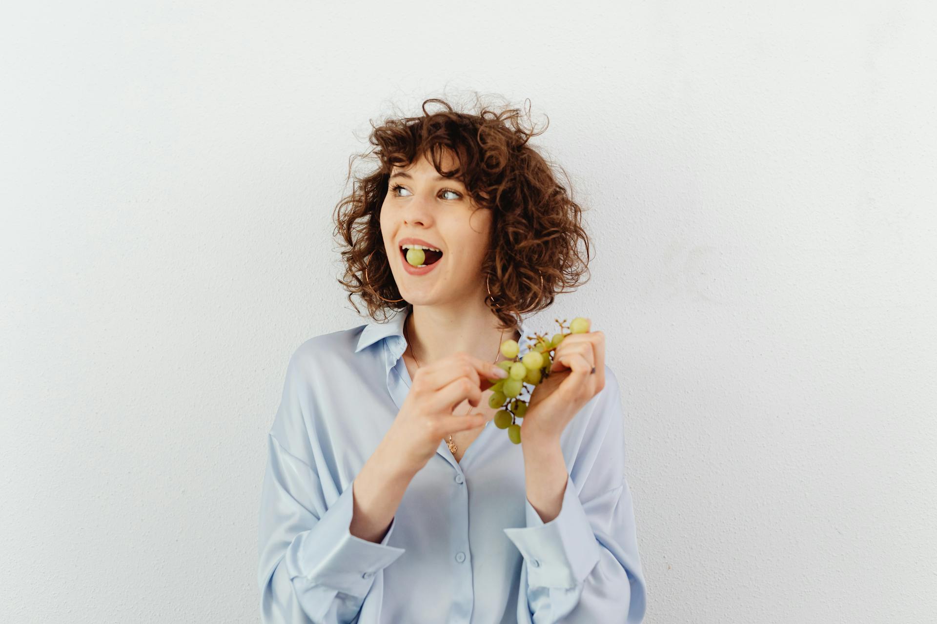Eine Frau mit Locken isst Weintrauben | Quelle: Pexels