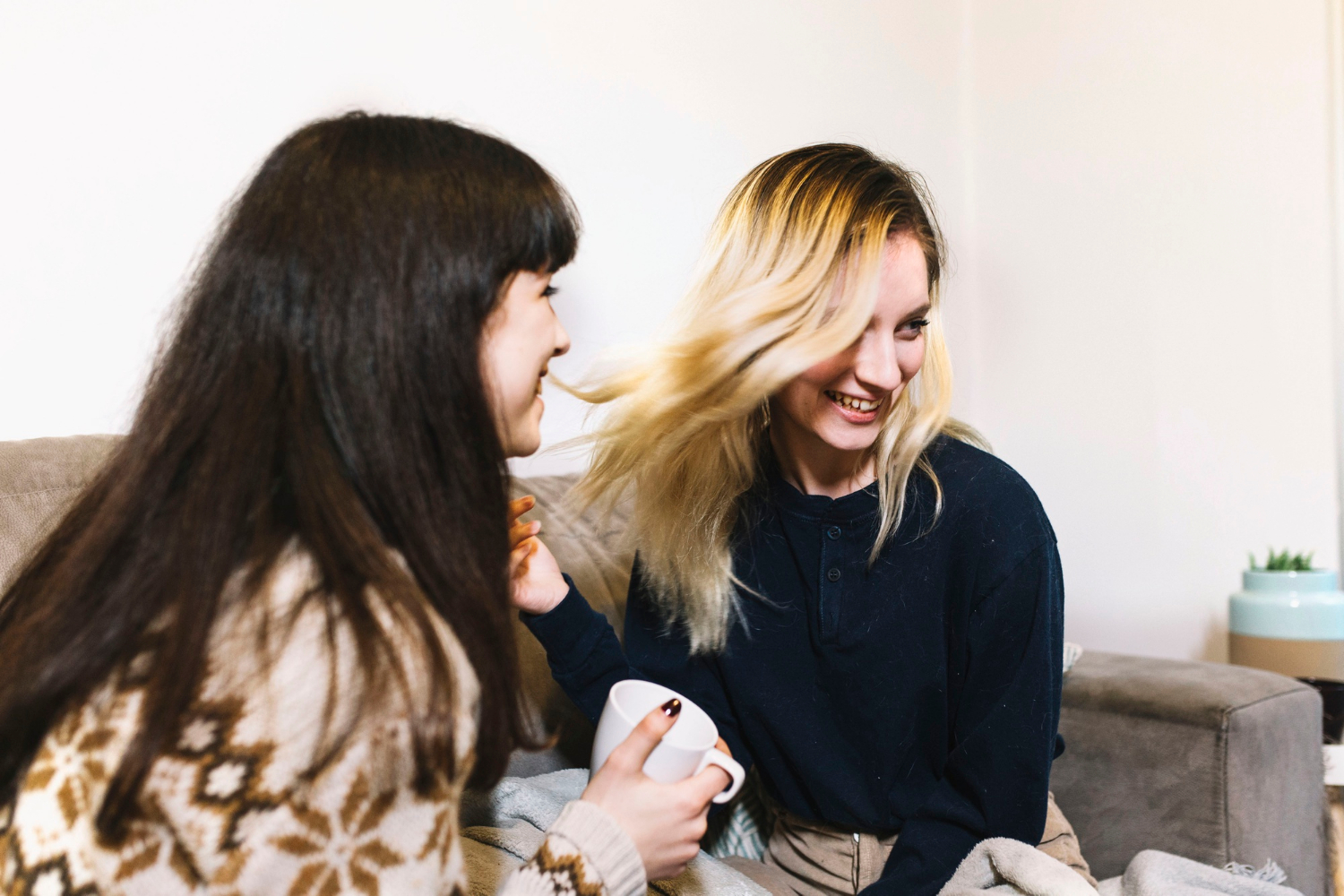 Zwei erfreute Frauen sitzen auf einer Couch | Quelle: Freepik