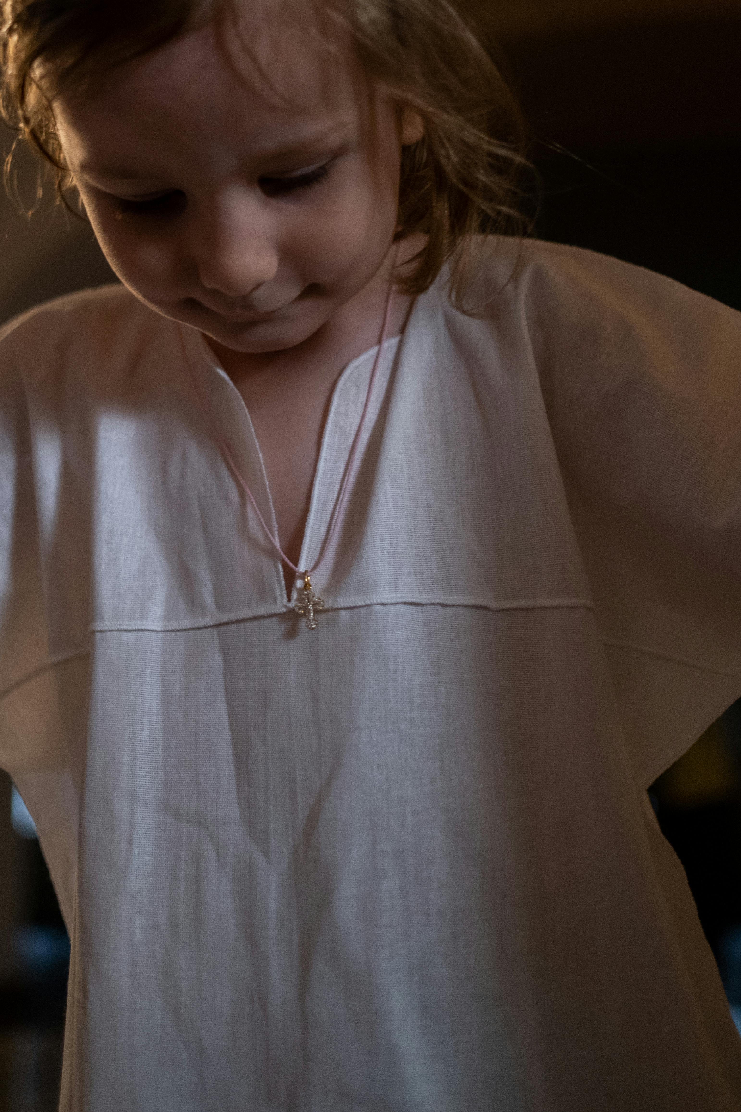 Ein kleines Mädchen in einem weißen Kleid schaut nach unten | Quelle: Pexels