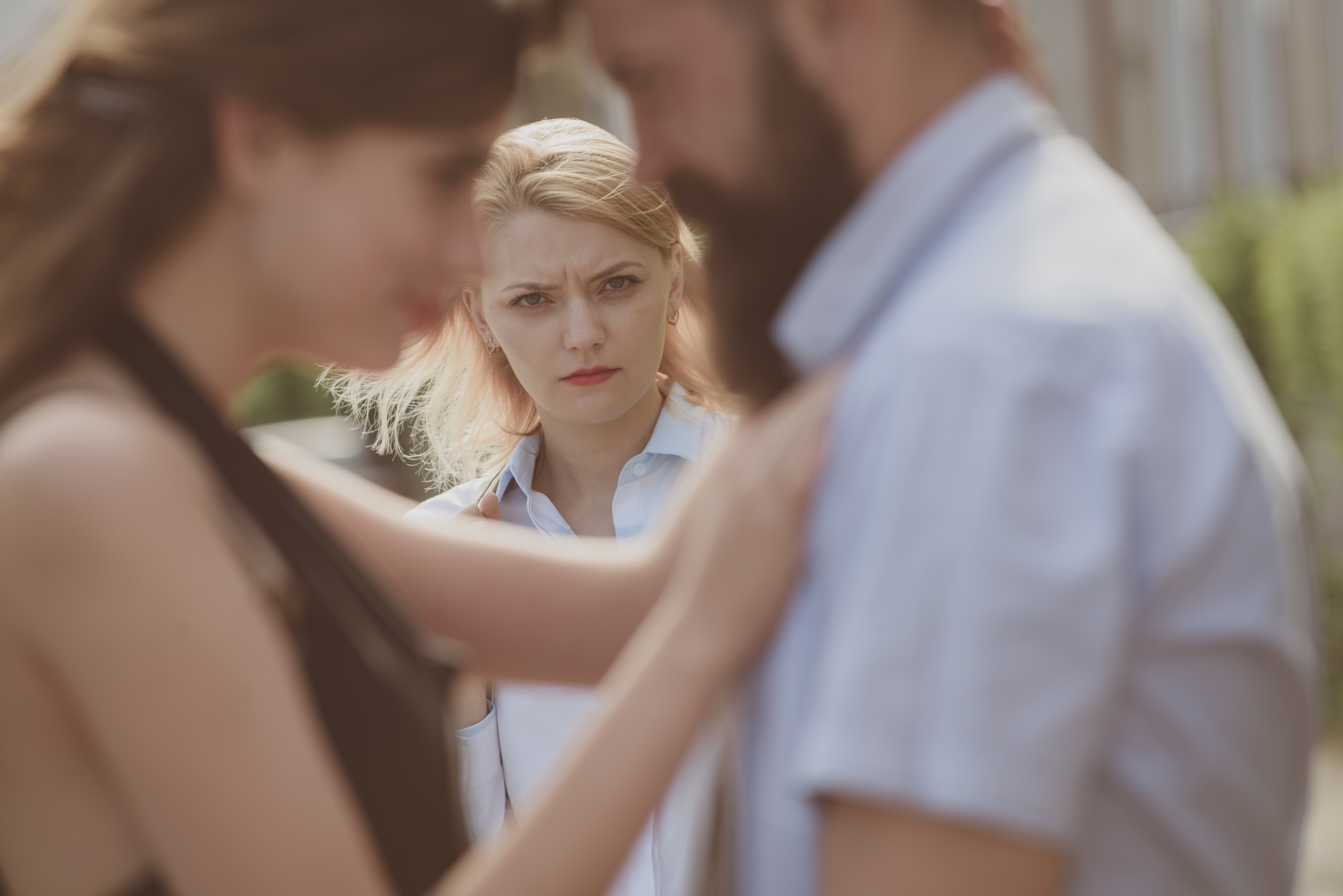 Eine Frau sieht zu, wie ihr Mann eine andere Frau umarmt | Quelle: Shutterstock