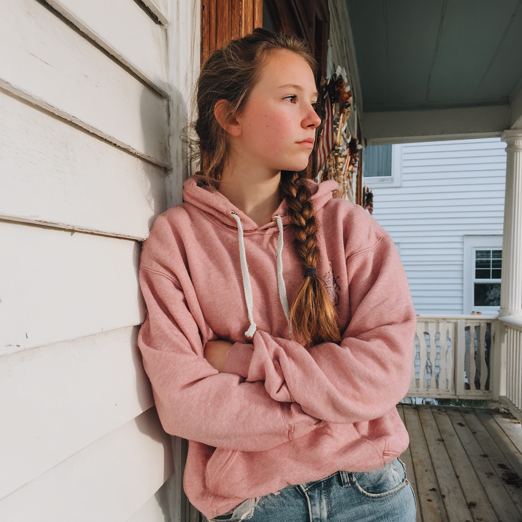 Ein Mädchen im Teenageralter steht auf einer Veranda | Quelle: Midjourney