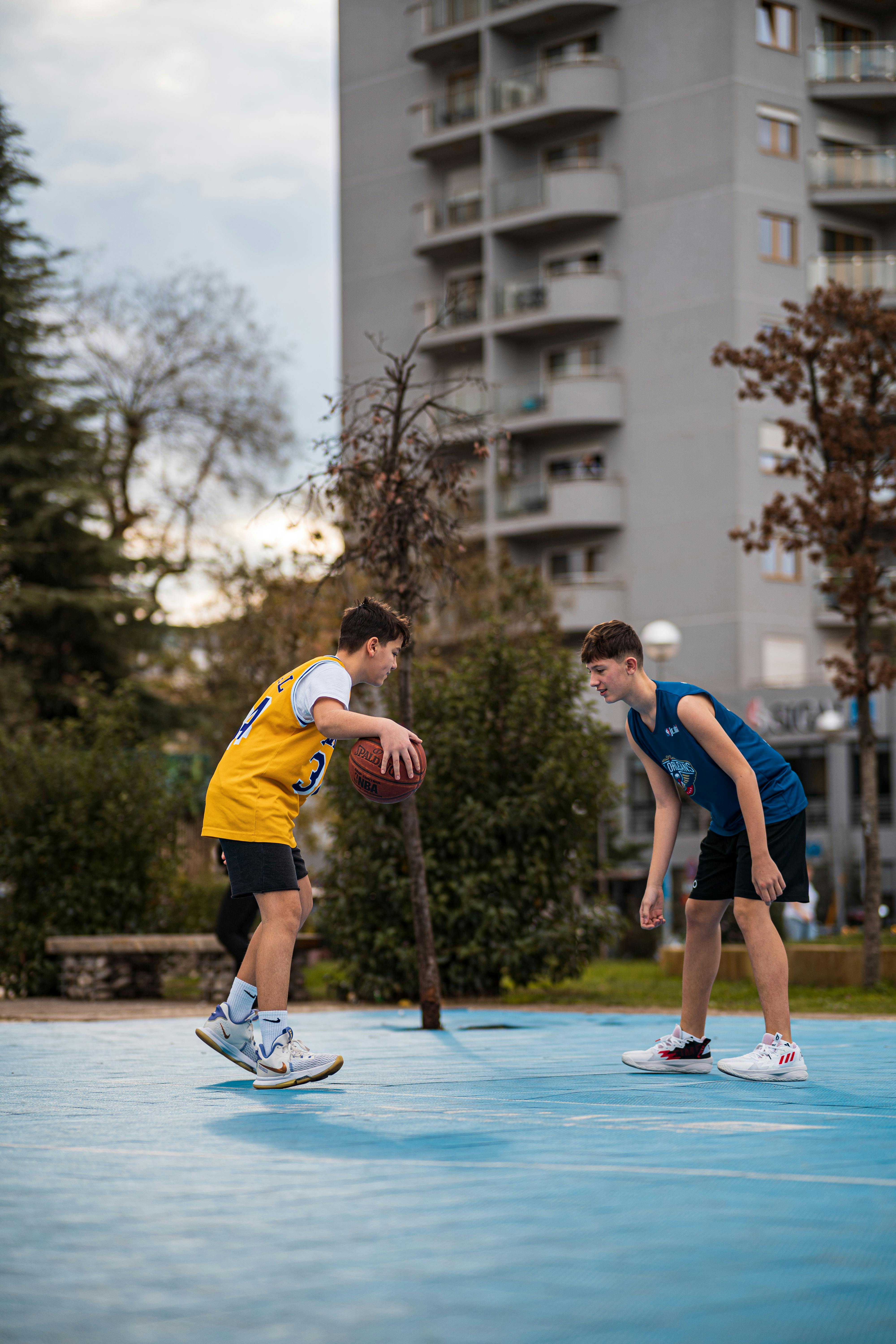 Zwei Jungen im Teenageralter spielen Basketball | Quelle: Pexels