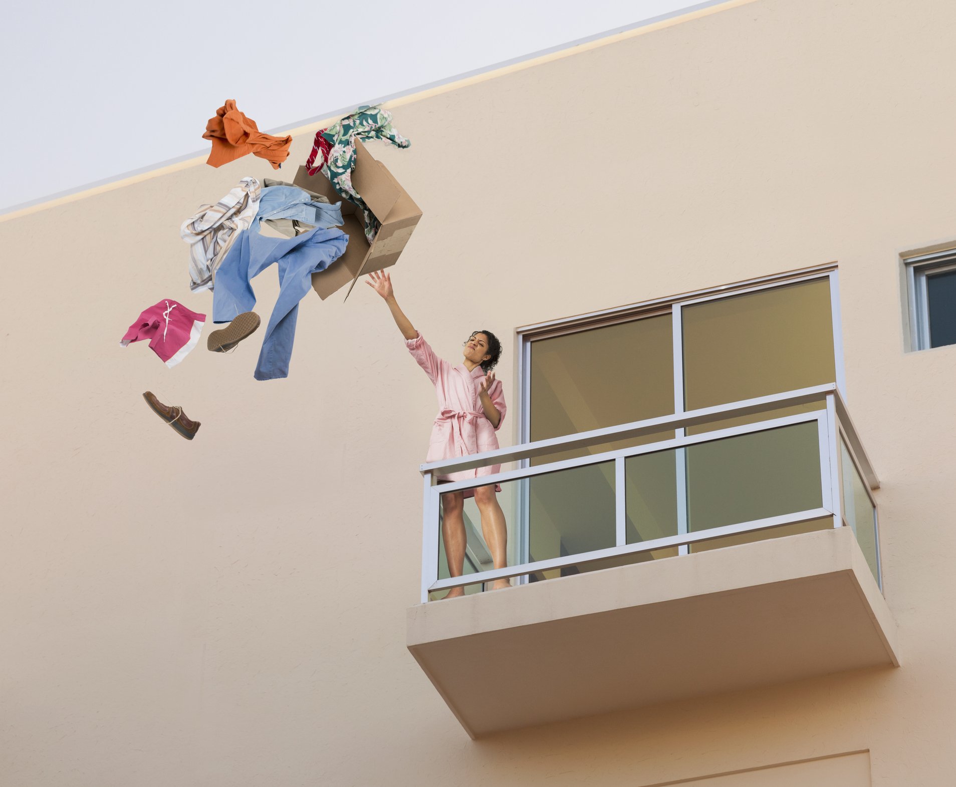 Frau schmeißt die Sachen des Freundes durch den Fenster. | Quelle: Getty Images