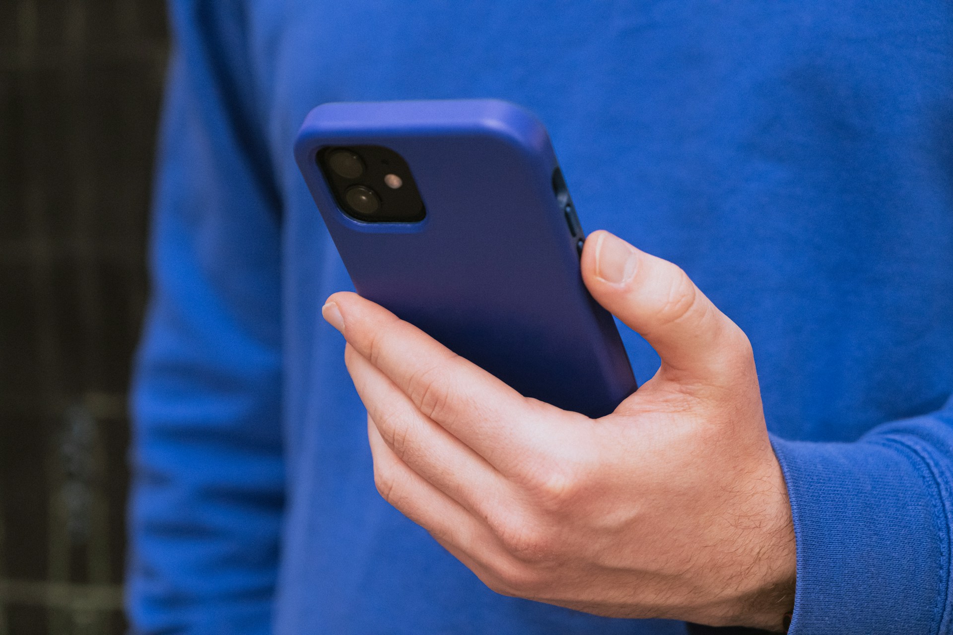 Ausgeschnittene Aufnahme eines Mannes, der sein Telefon hält | Quelle: Unsplash