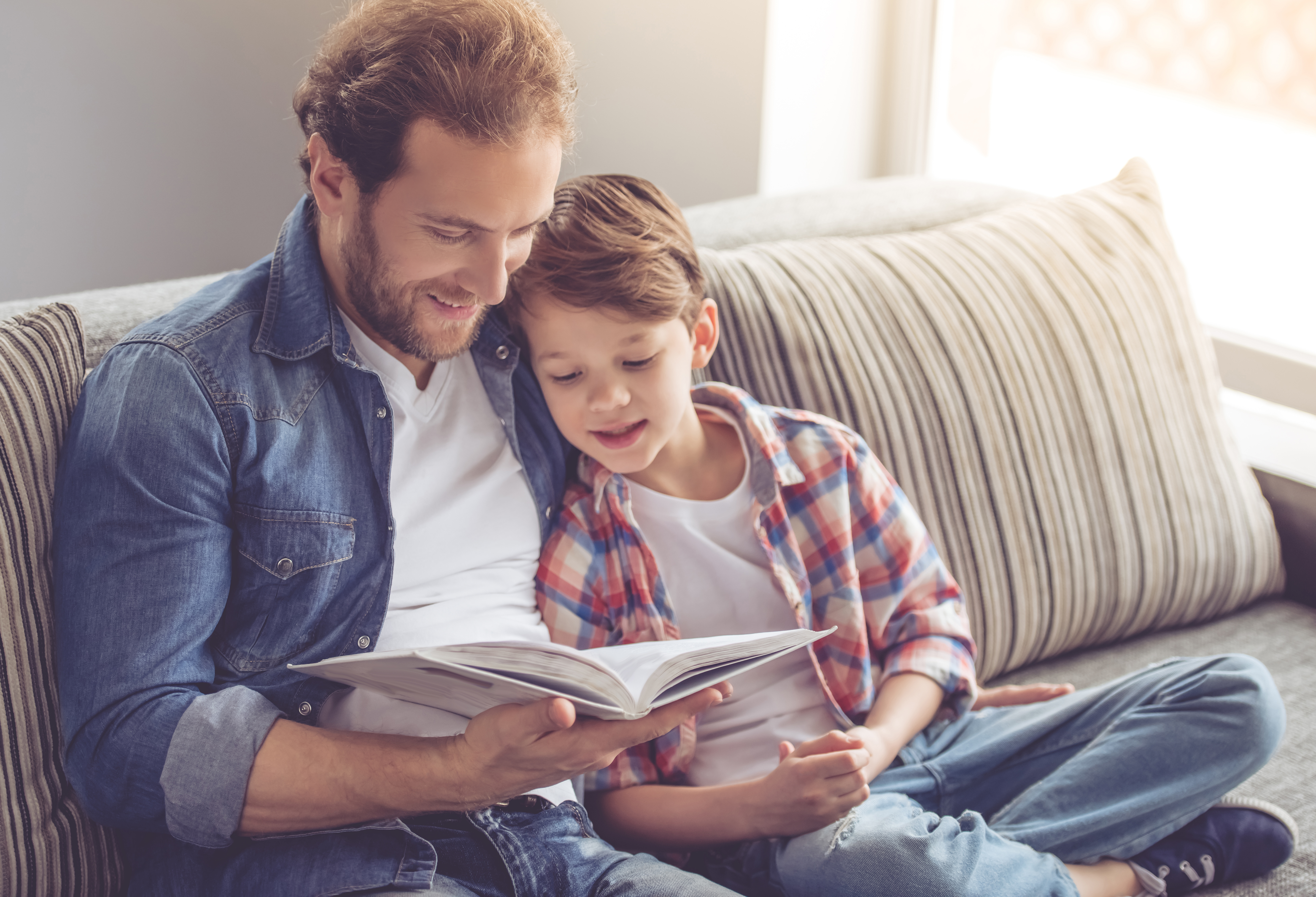 Vater und Sohn lesen ein Buch und lächeln | Quelle: Shutterstock