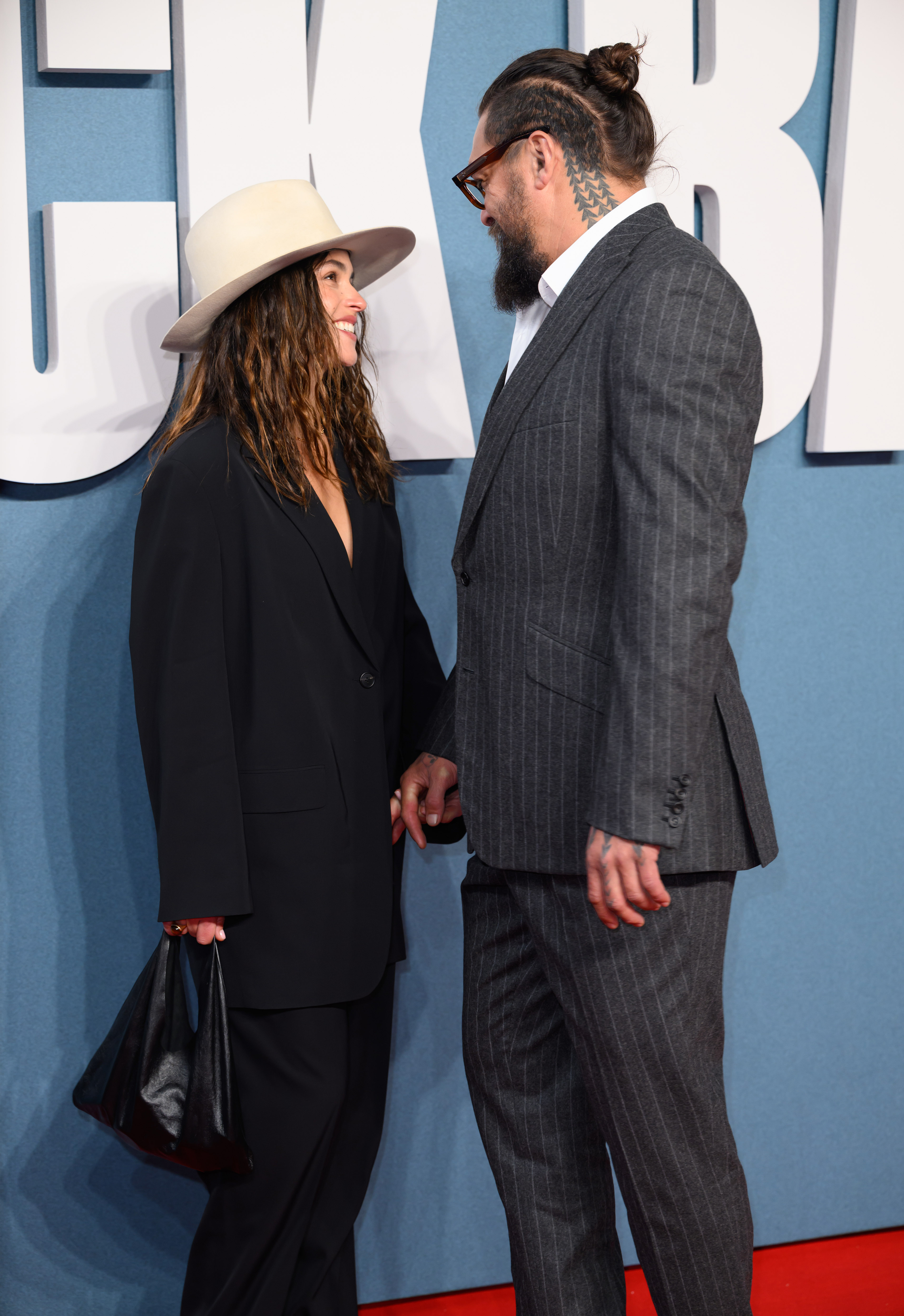 Adria Arjona und Jason Momoa tauschen bei der Veranstaltung ein Lächeln aus. | Quelle: Getty Images