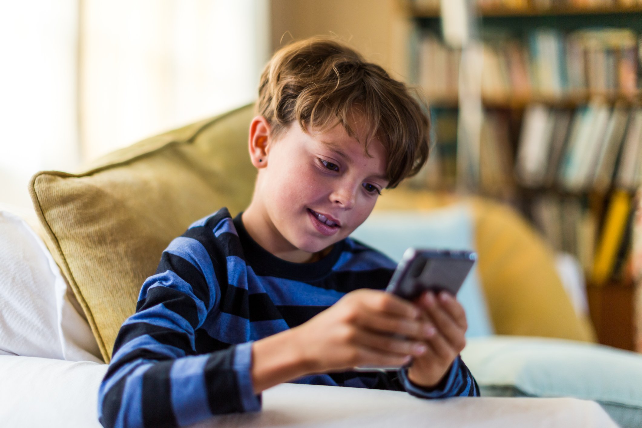 Junge, der allein auf Smartphone im Wohnzimmer spielt I Quelle: Getty Images