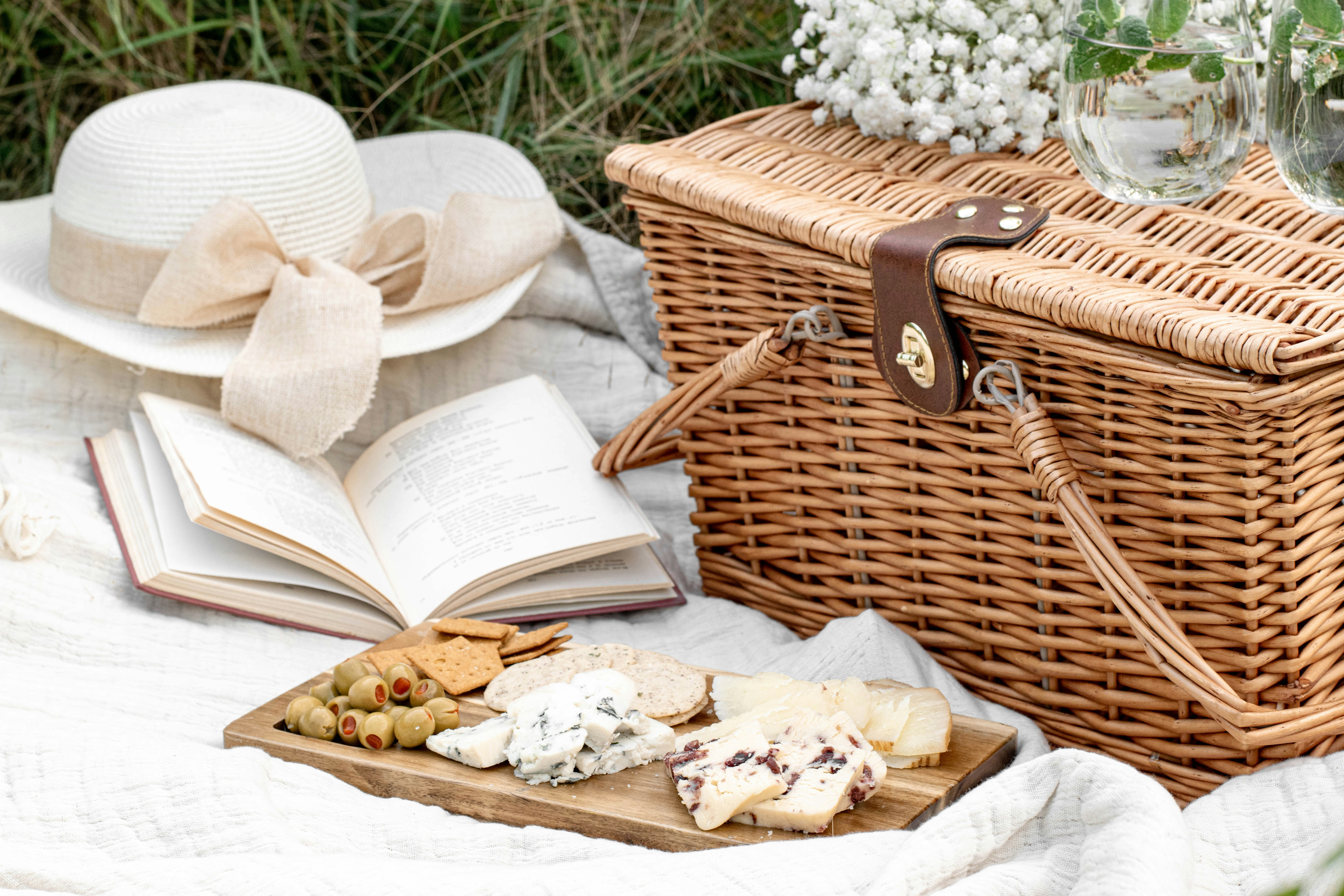 Ein Picknickkorb, Essen, ein Buch und ein Hut | Quelle: Unsplash