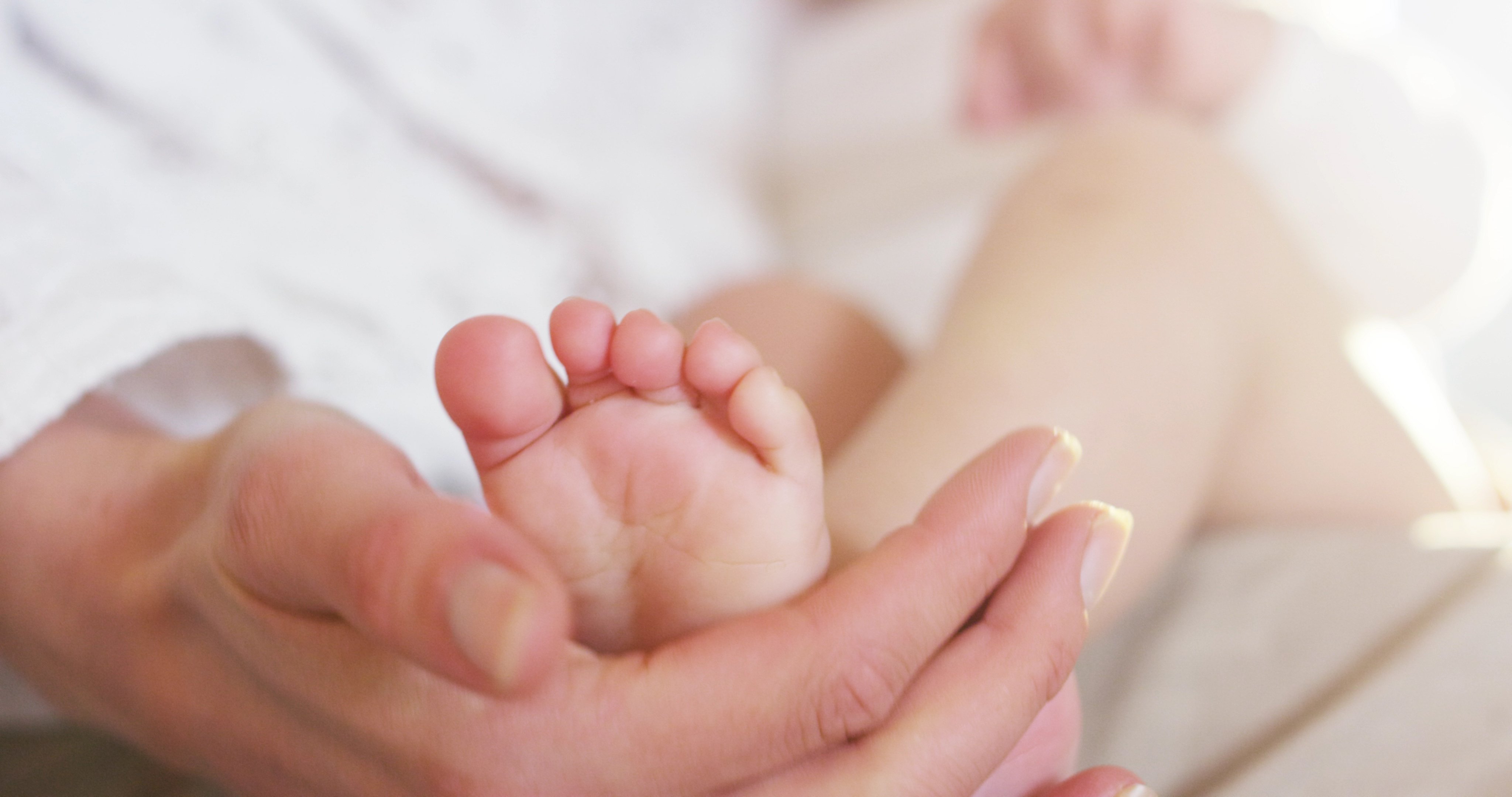 Die Hände einer Mutter berühren sanft die Füße ihres Babys | Quelle: Shutterstock