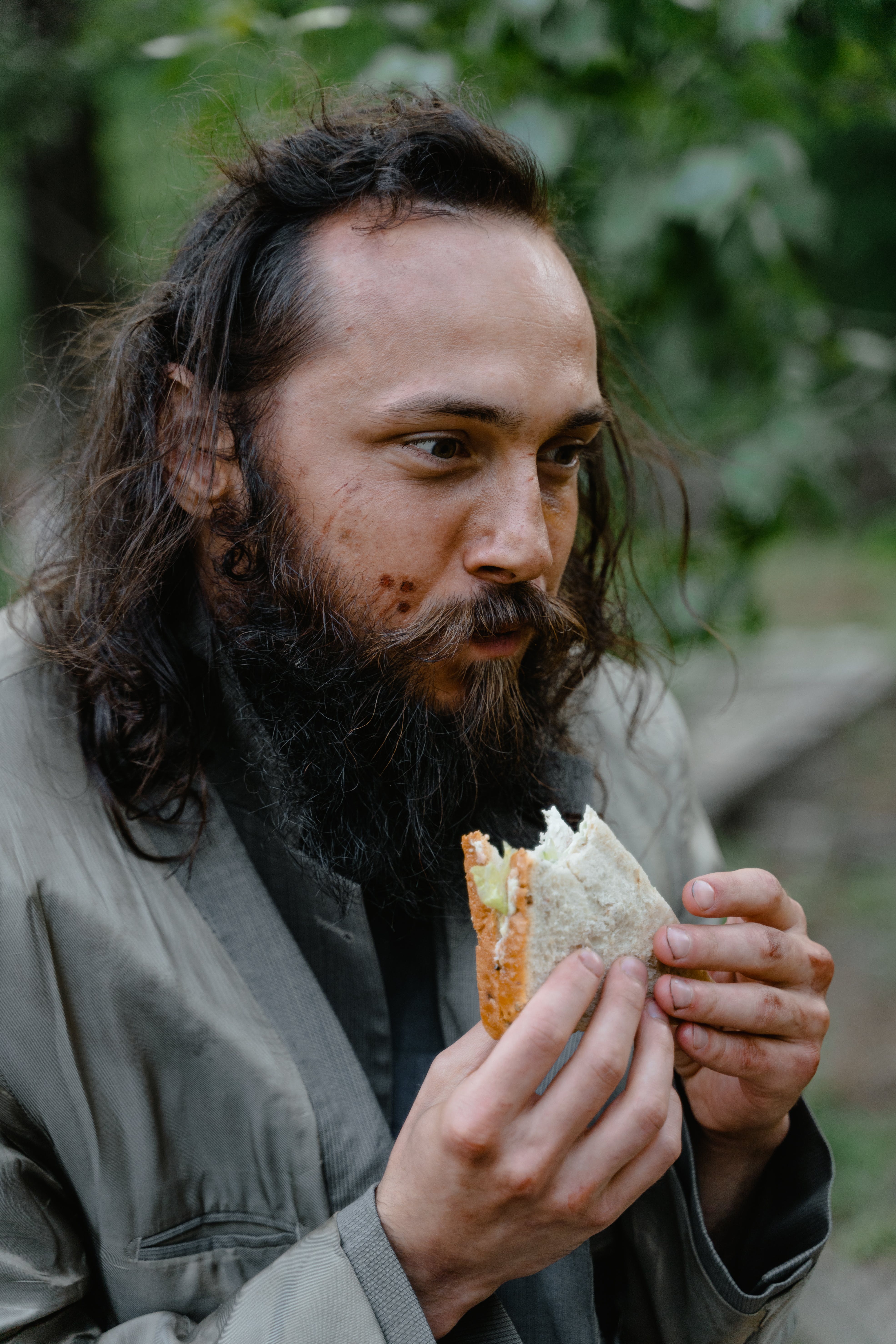 Ein obdachloser Mann sieht glücklich aus, während er etwas isst | Quelle: Pexels