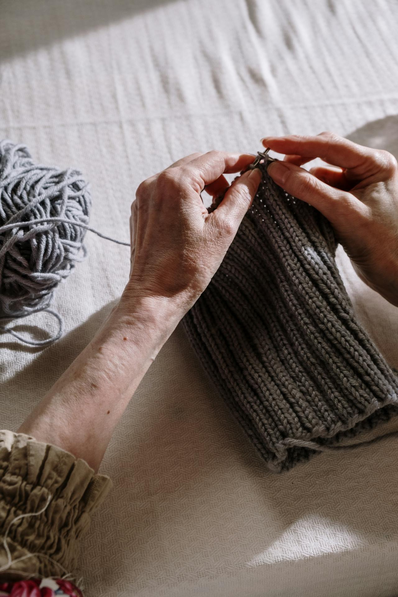 Nahaufnahme einer älteren Frau beim Stricken eines grauen Fadens | Quelle: Pexels