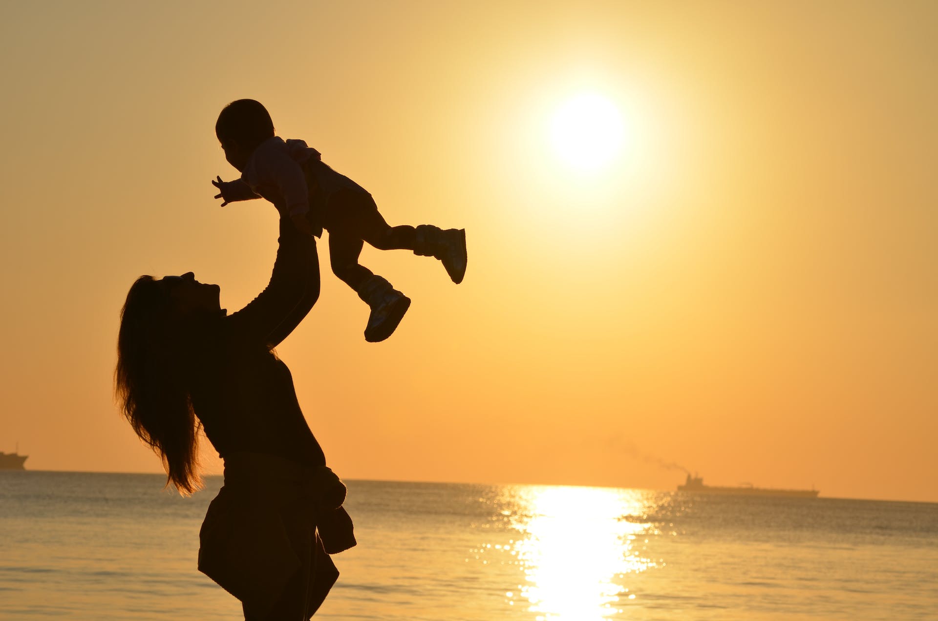 Silhouette einer Mutter, die ihr Baby während der goldenen Stunde am Strand trägt | Quelle: Pexels