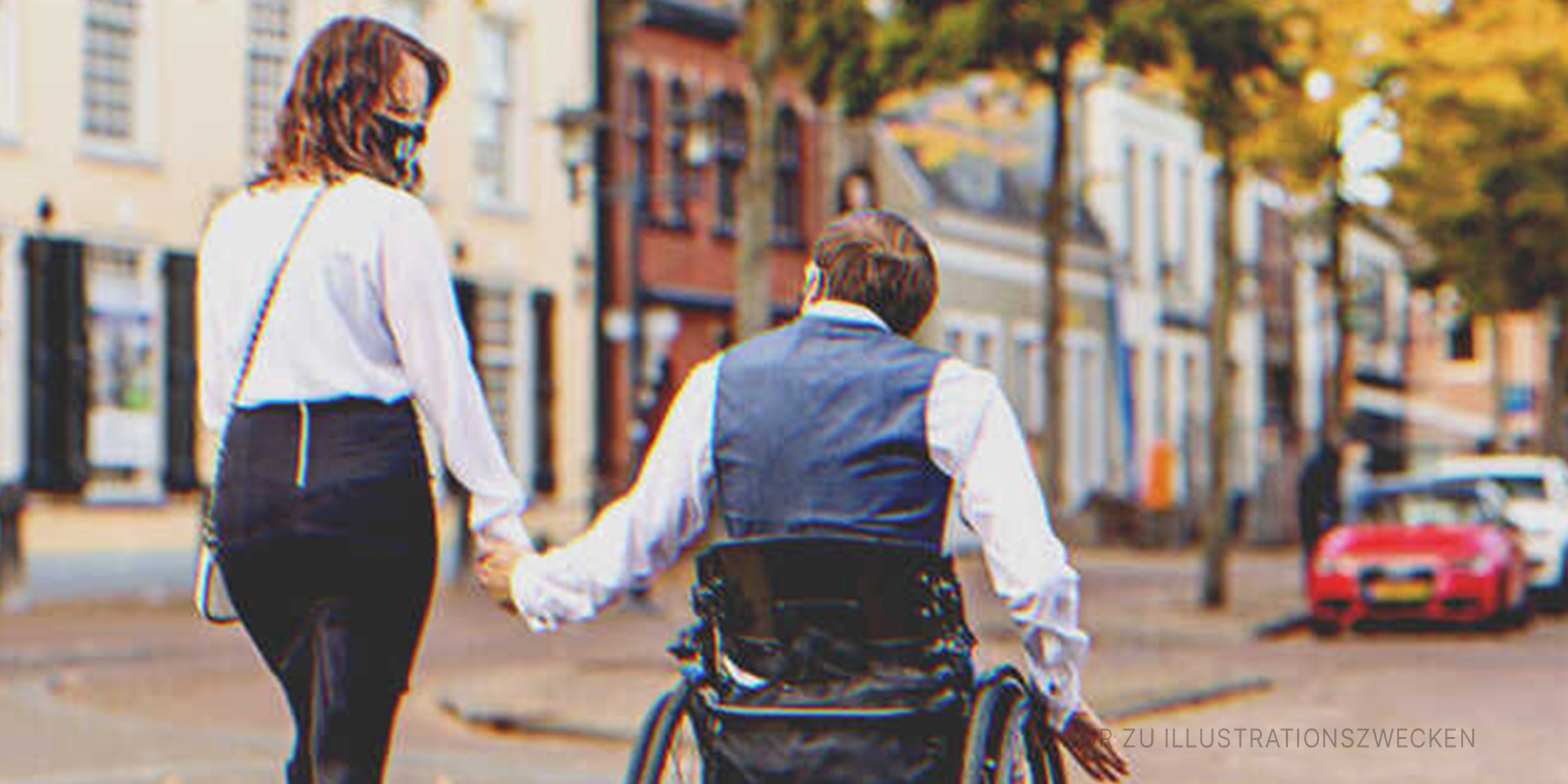Ein im Rollstuhl sitzender Mann mit seiner Partnerin im Freien. | Quelle: Getty Images