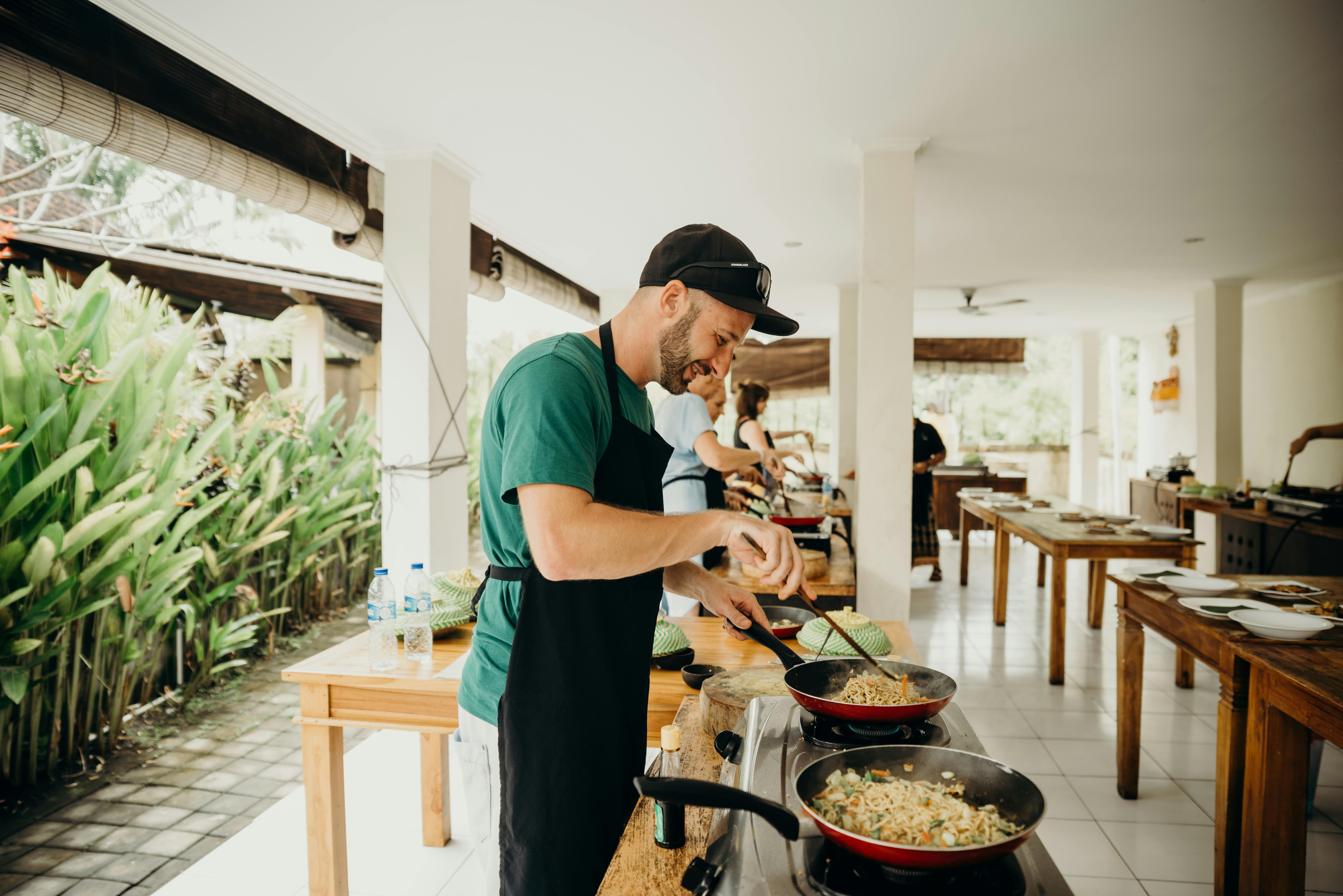 Ein Mann in schwarzer Schürze beim Kochen in einem Kochwettbewerb | Quelle: Pexels