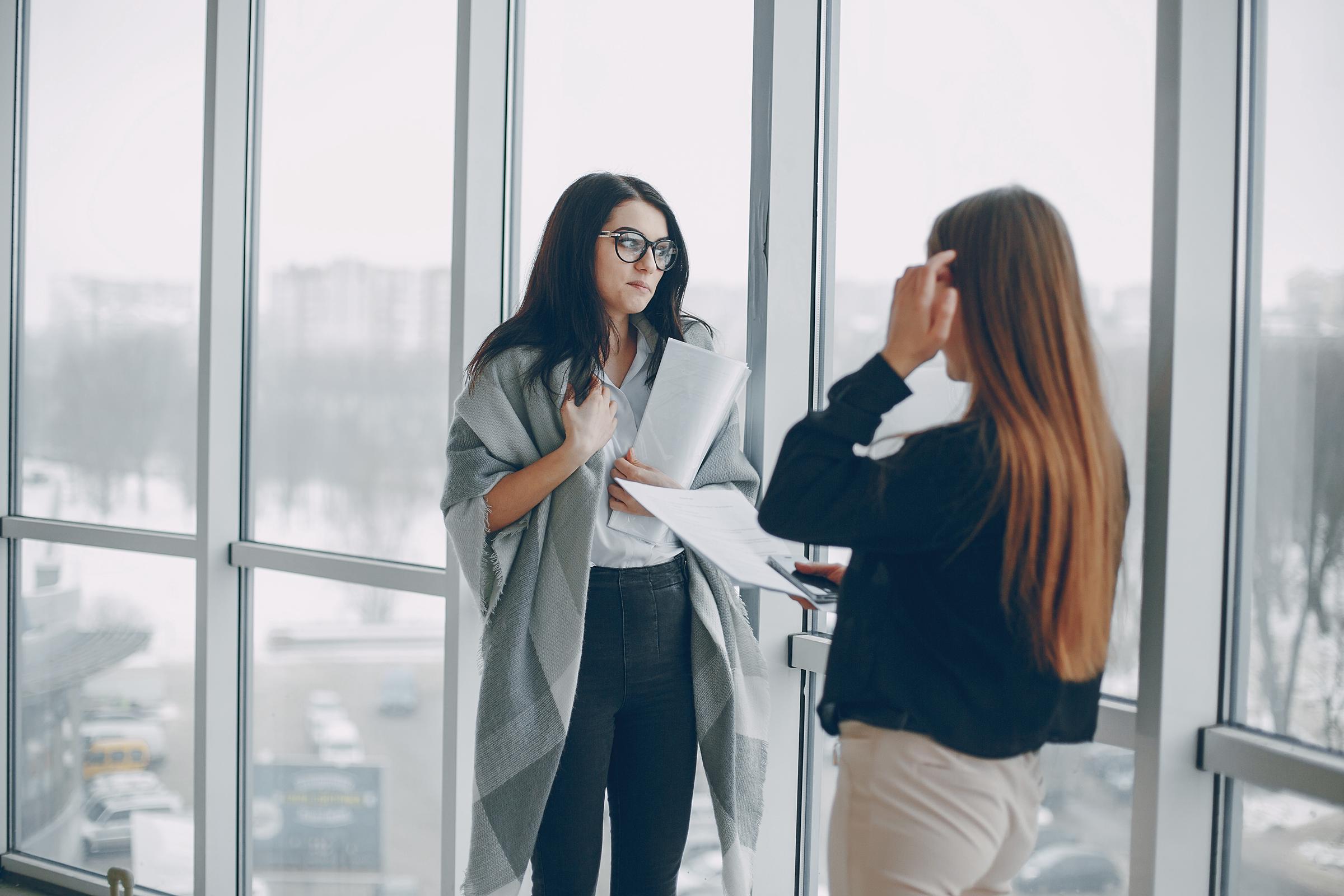 Zwei Frauen unterhalten sich am Arbeitsplatz | Quelle: Freepik