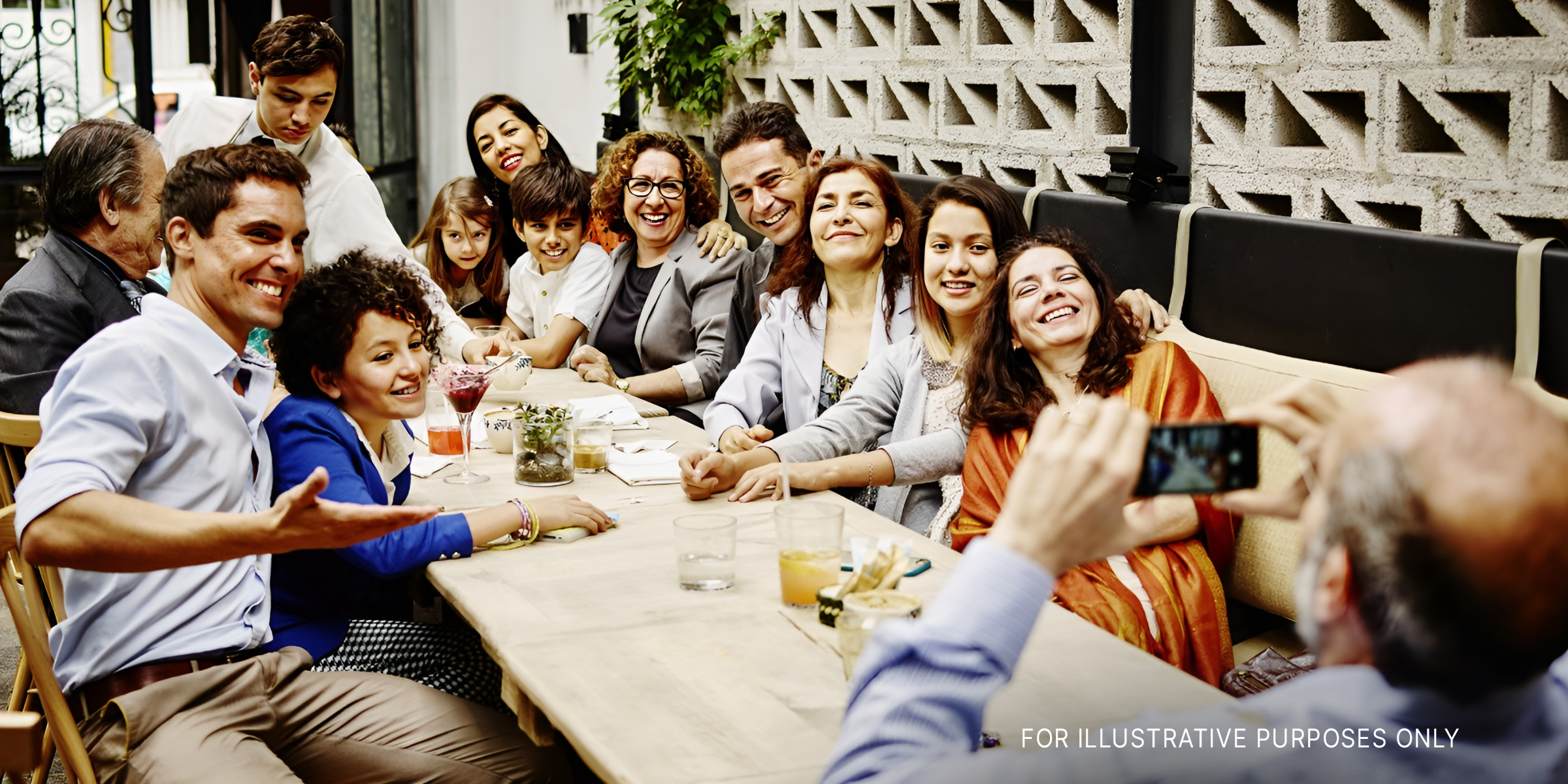 Ein Mann macht ein Familienfoto mit seinem Smartphone während einer Dinnerparty in einem Restaurant | Quelle: Getty Images