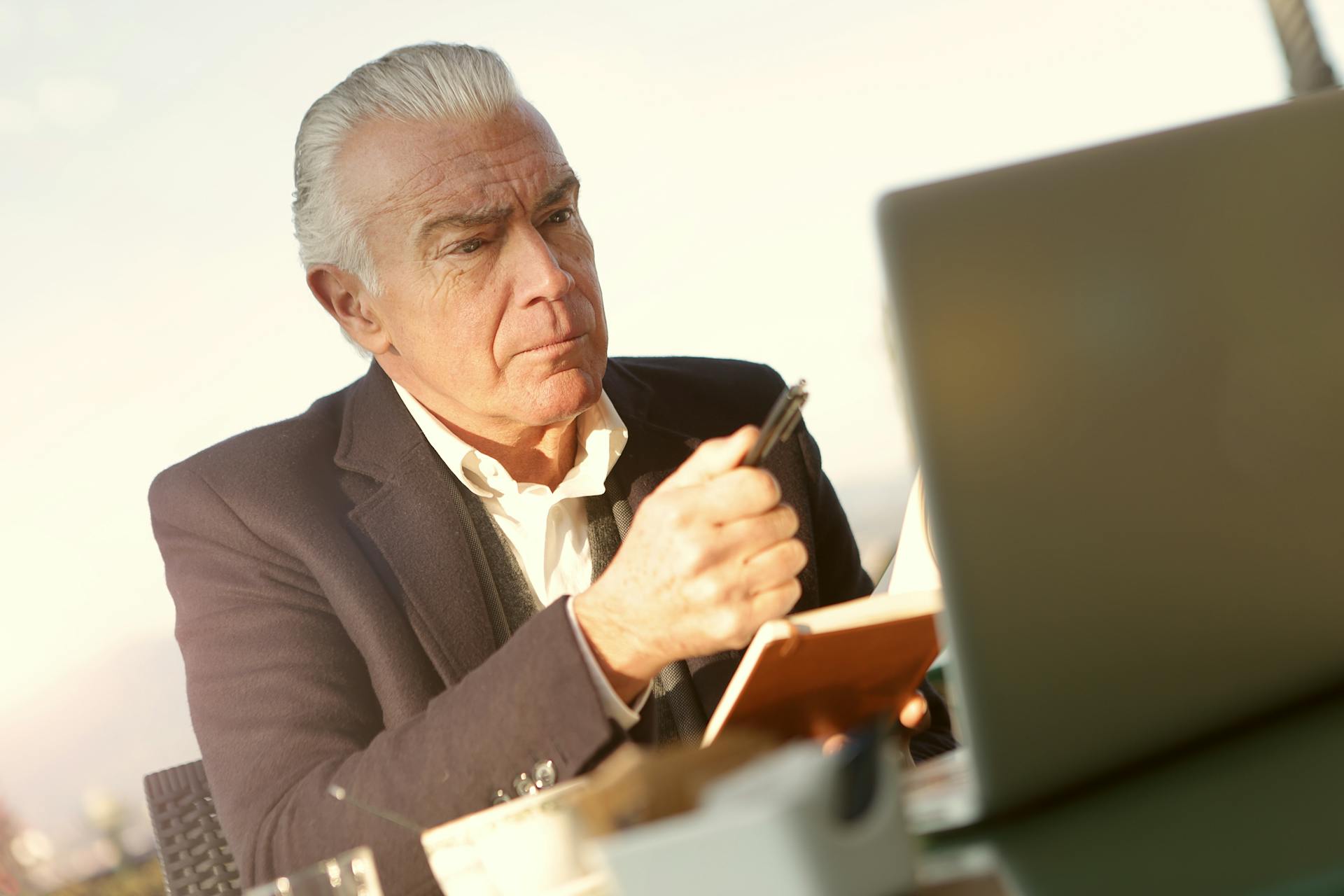 Ein strenger älterer Mann sitzt vor seinem Laptop in seinem Büro | Quelle: Pexels