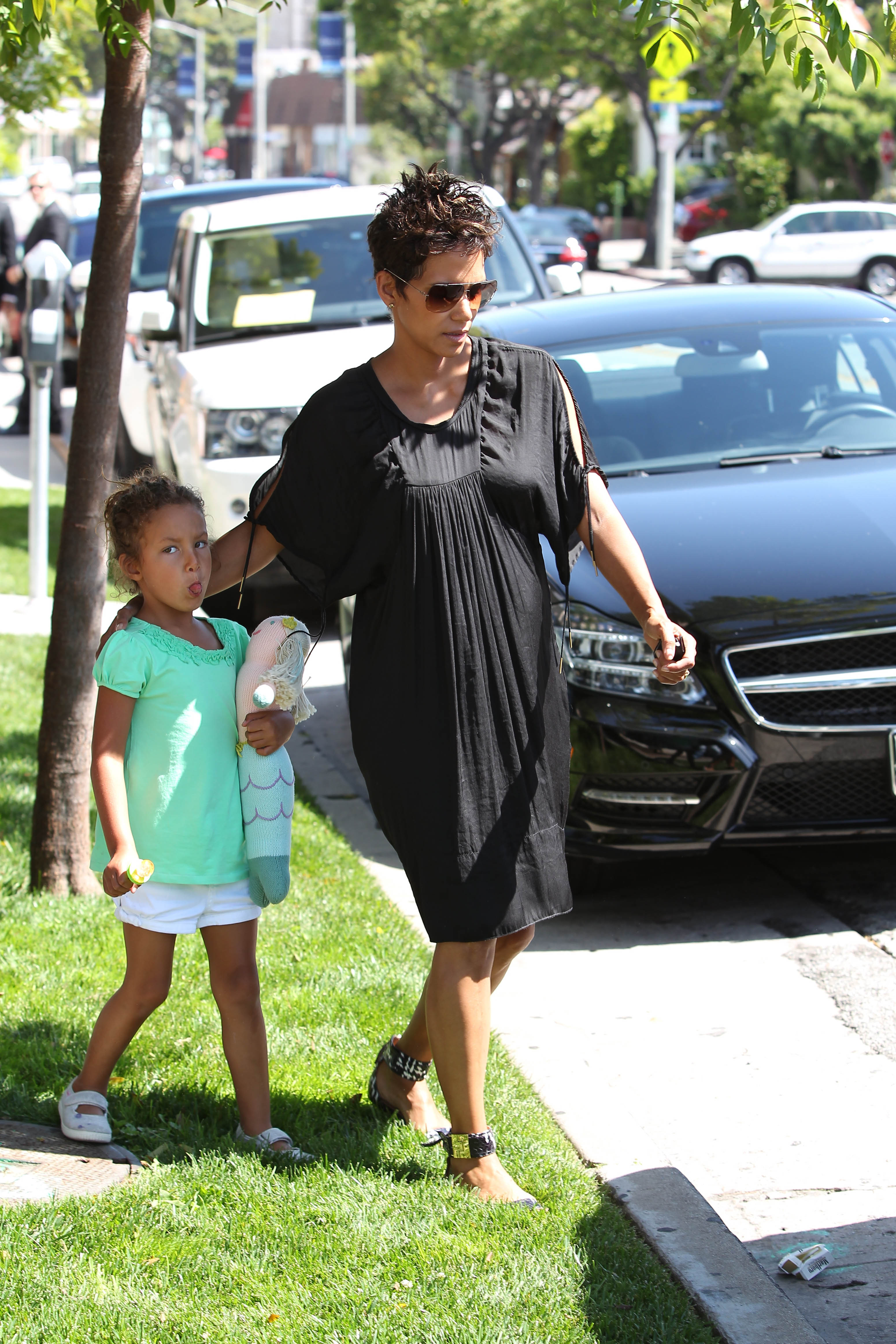 Die kleine Nahla streckte verspielterweise die Zunge heraus, während sie bei einem Spaziergang mit Halle Berry eine Meerjungfrauenpuppe im Arm hielt – ein rührender Einblick in die unbeschwerte Kindheit, für deren Schutz ihre Mutter gekämpft hat. | Quelle: Getty Images.