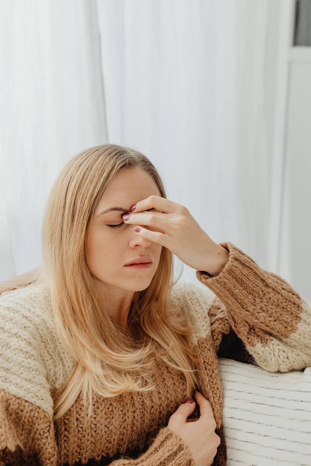 Eine stirnrunzelnde Frau, die sich die Augenbrauen reibt ⏐ Quelle: Pexels