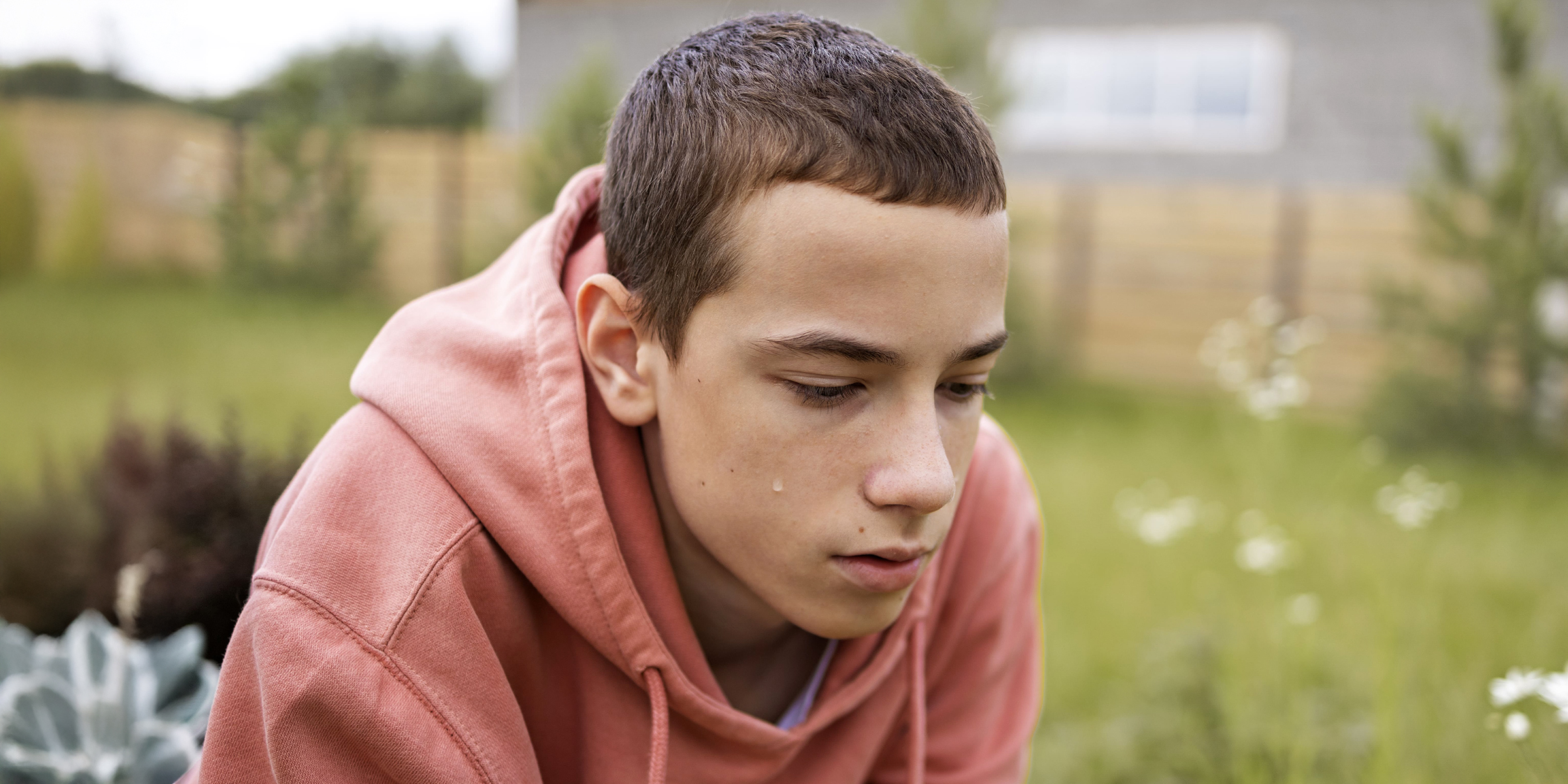 Ein deprimierter Teenager, der mit gesenktem Blick im Freien sitzt | Quelle: Freepik