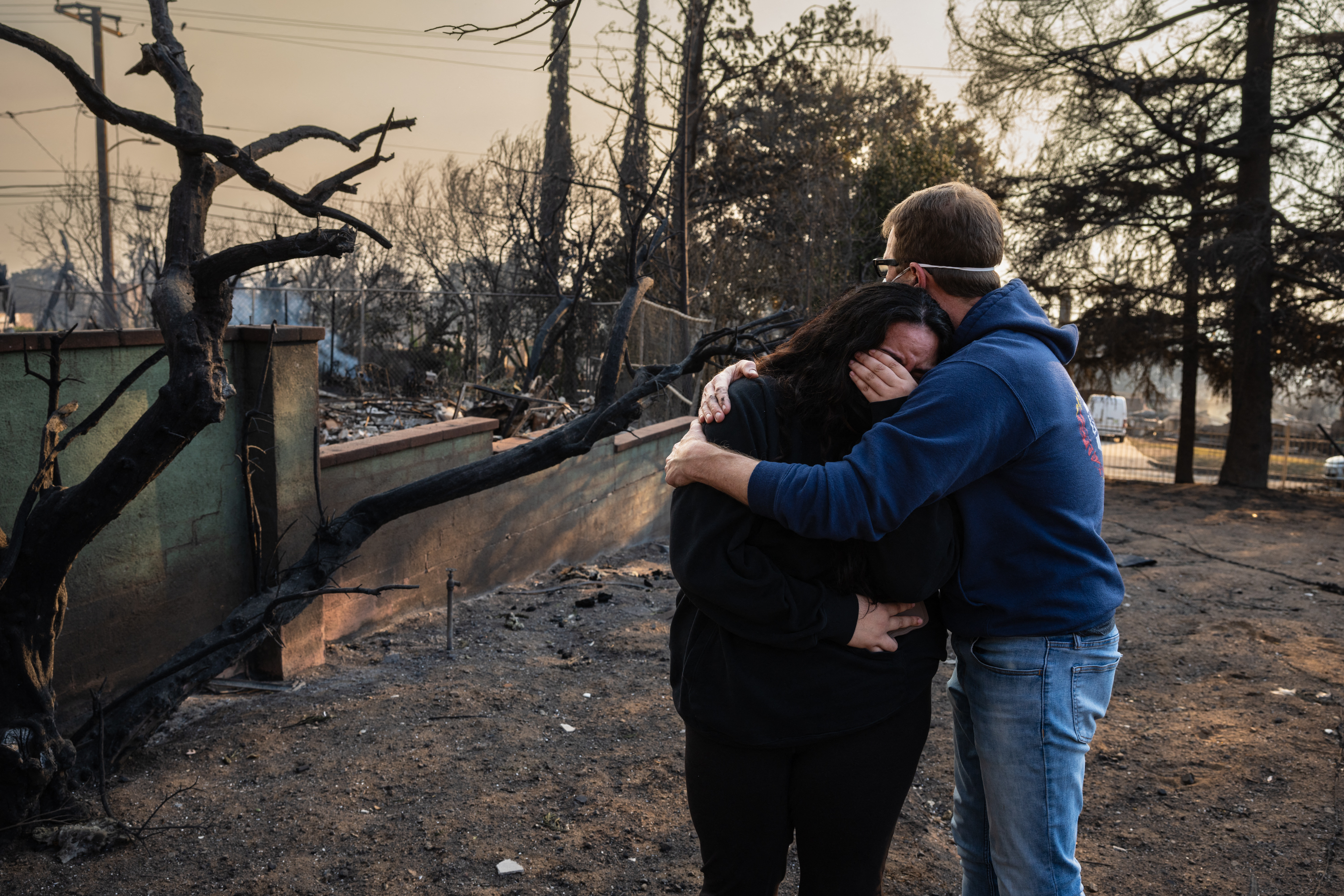 Ein Mann umarmt seine Tochter in den verkohlten Ruinen ihres Hauses, das beim Eaton-Feuer am 9. Januar 2025 in Altadena, Kalifornien, verbrannt ist. | Quelle: Getty Images