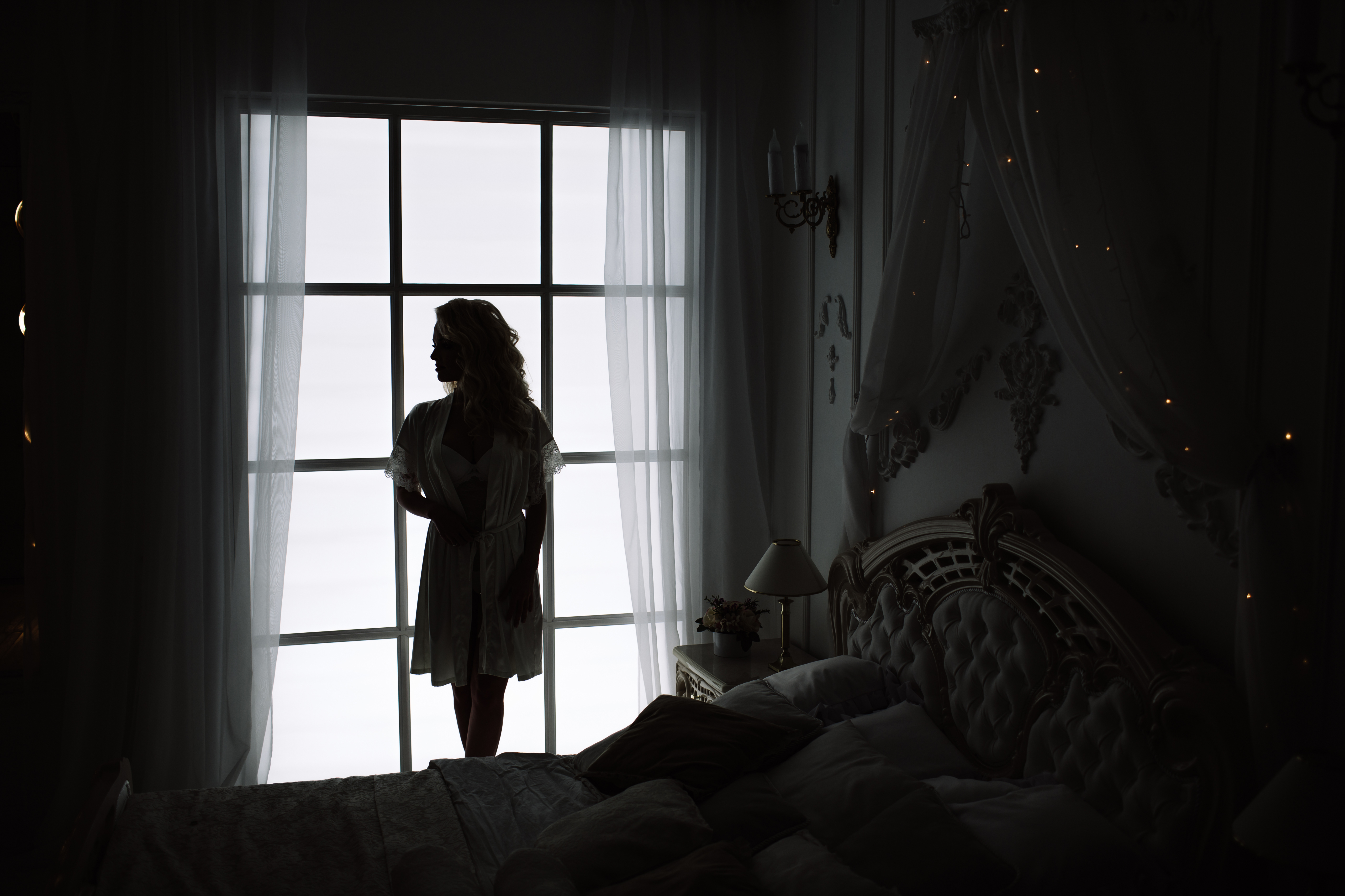 Die Silhouette einer Frau vor dem Fenster eines Schlafzimmers | Quelle: Shutterstock